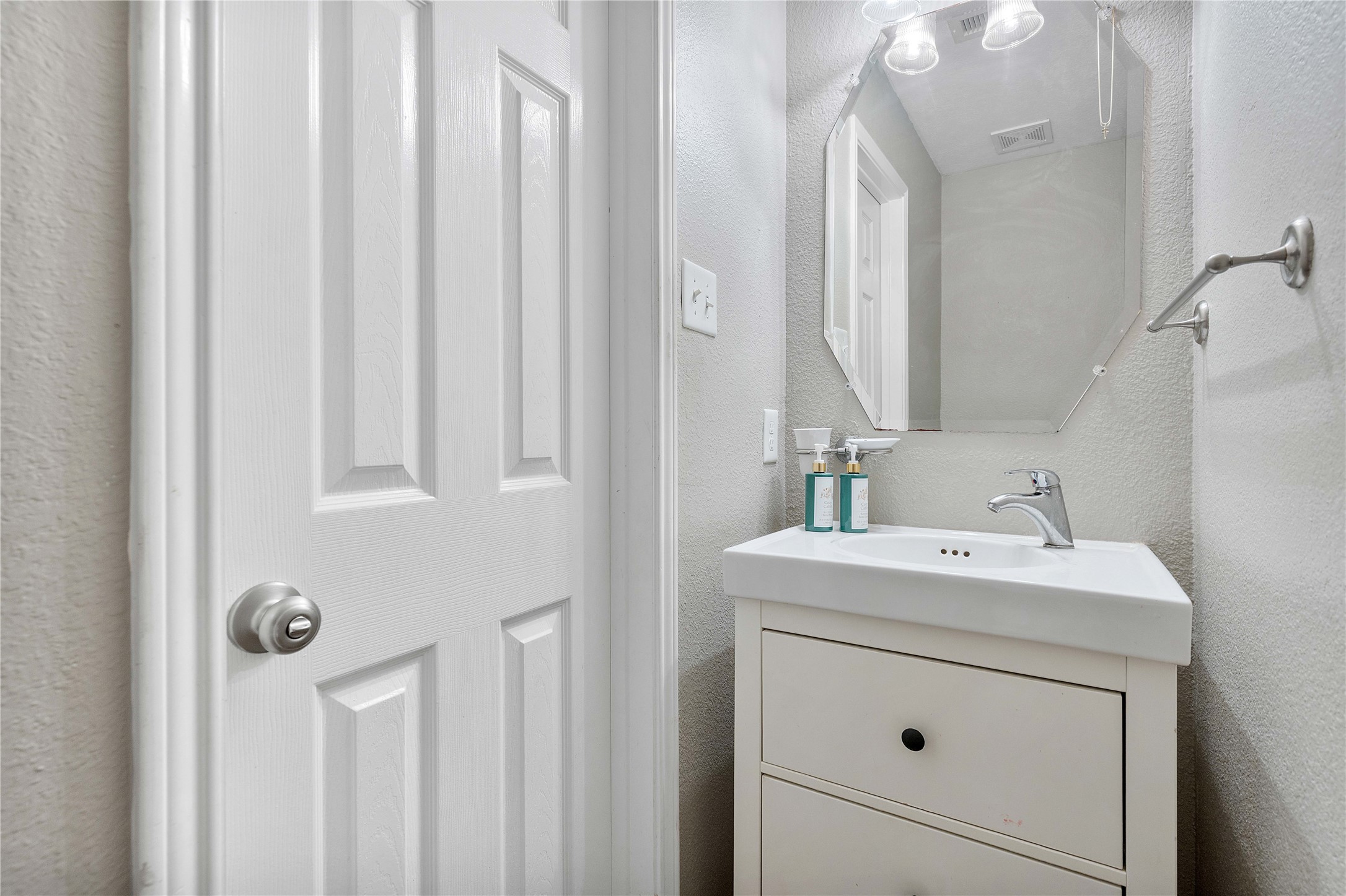 Charming half-bathroom featuring a sleek vanity with modern fixtures, complemented by a stylish mirror and neutral tones.