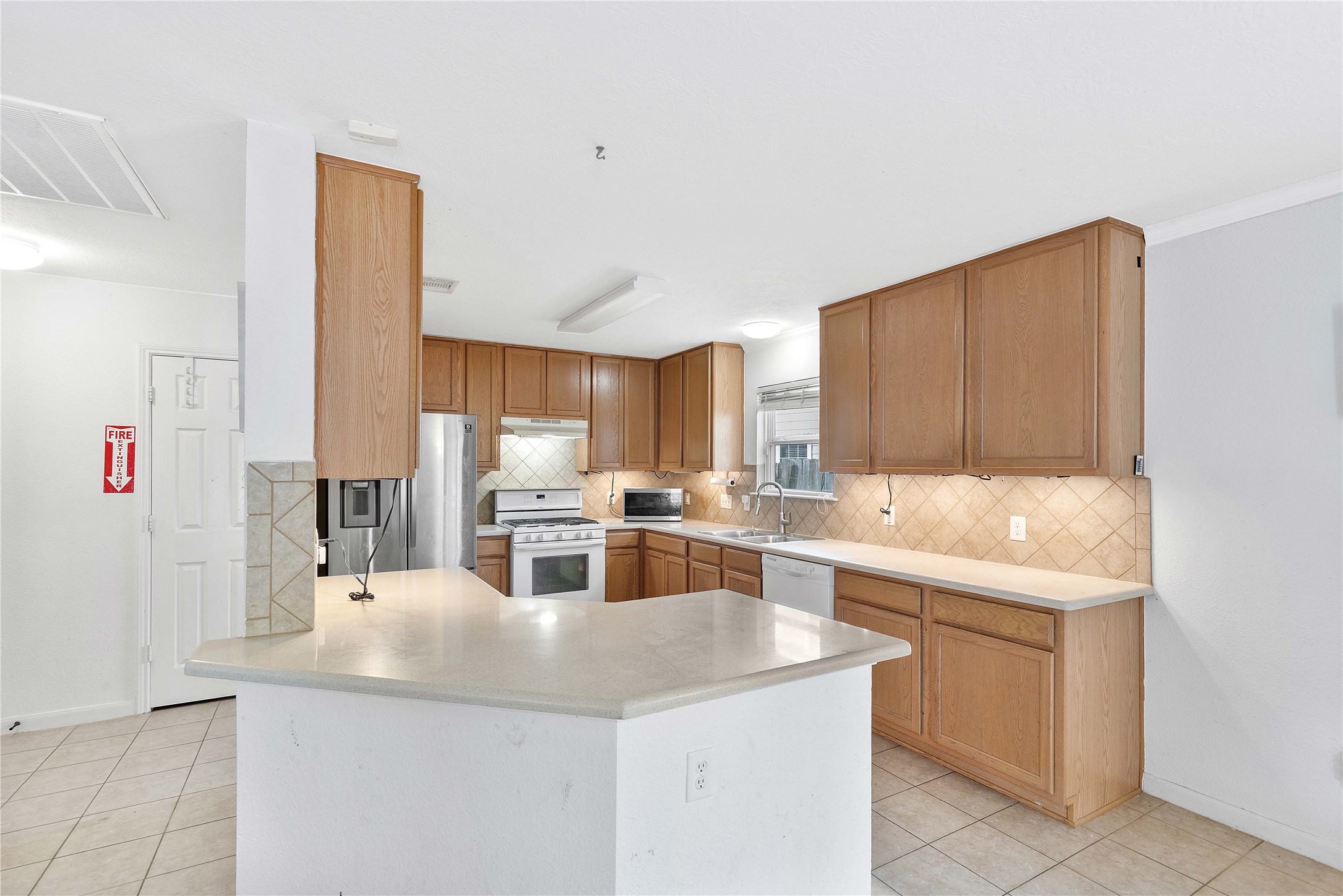 Spacious kitchen with abundant wood cabinetry, sleek countertops, and modern stainless steel appliances, complemented by a large island and tile flooring for easy maintenance.