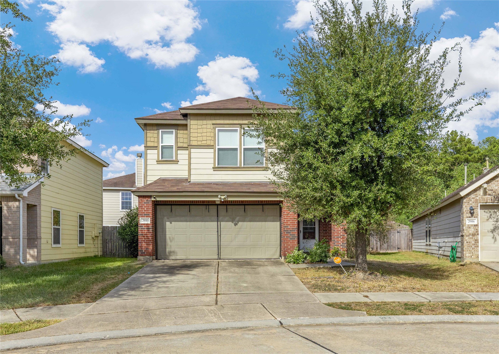 Charming two-story home with a brick facade and attached two-car garage, nestled in a quiet suburban neighborhood.