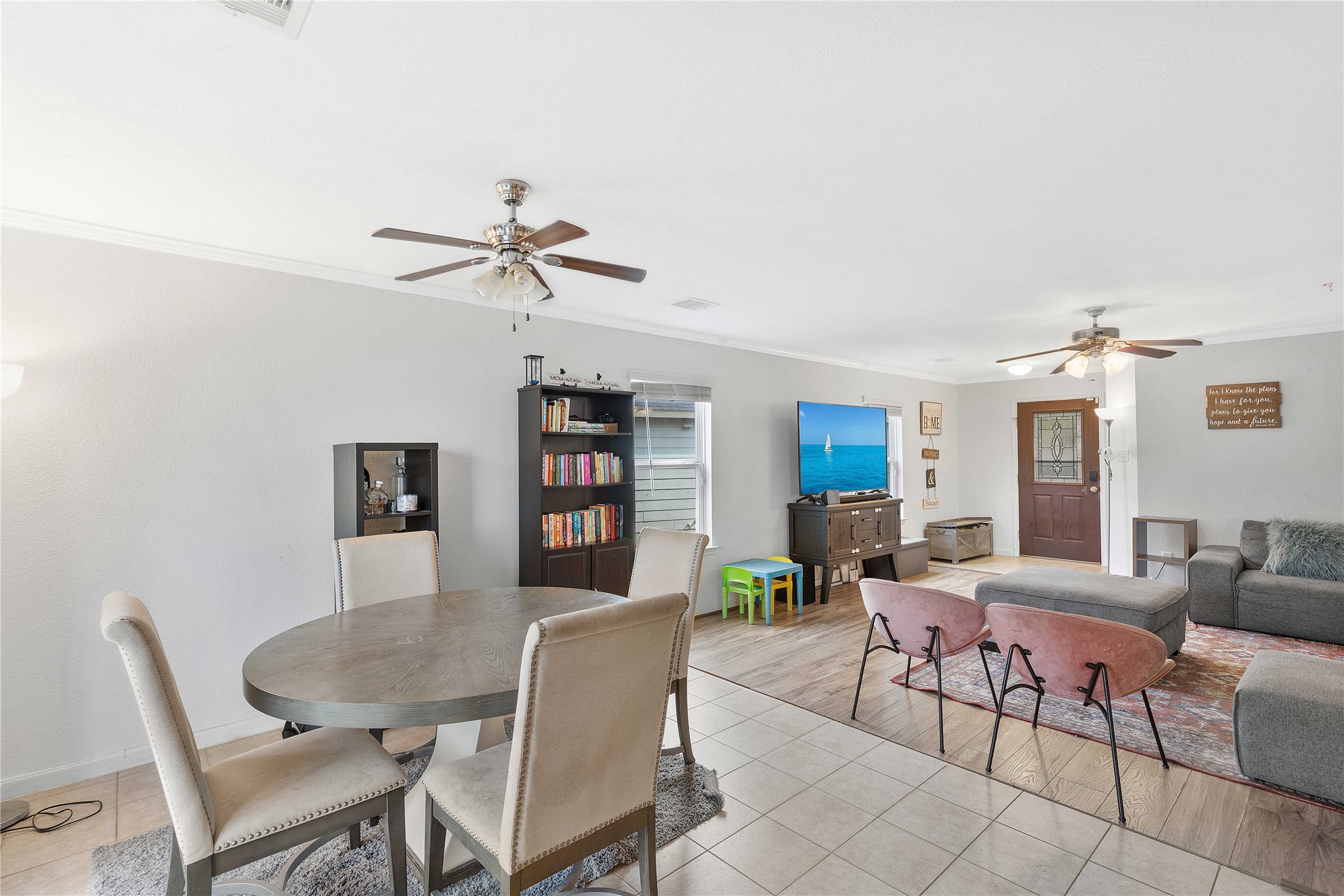 Spacious open-concept living area featuring a cozy dining space, stylish ceiling fans, and a comfortable seating arrangement ideal for relaxation and entertainment.