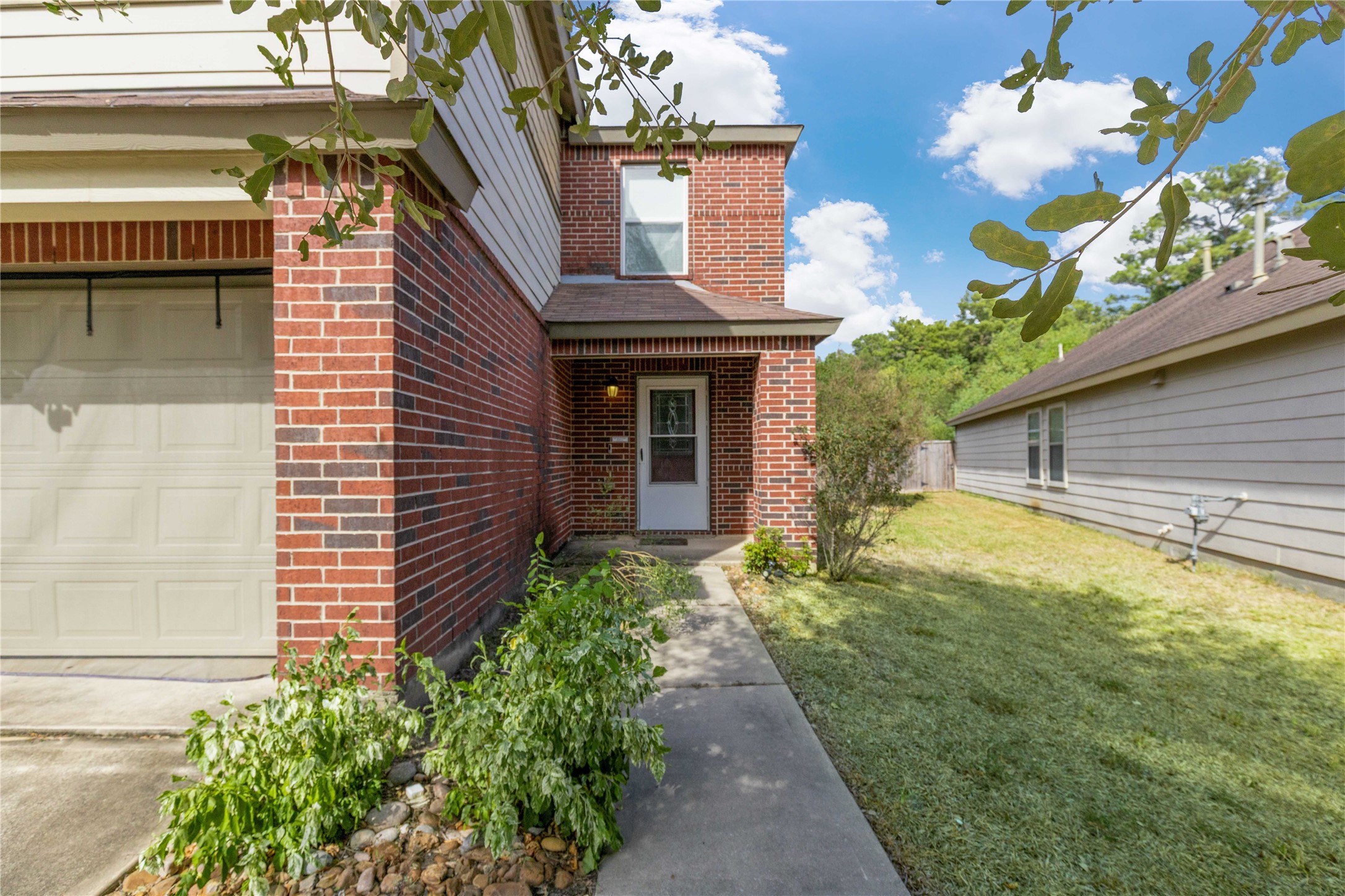 Charming brick exterior with a welcoming walkway leads to the front entrance, complemented by a well-maintained lawn and lush greenery.