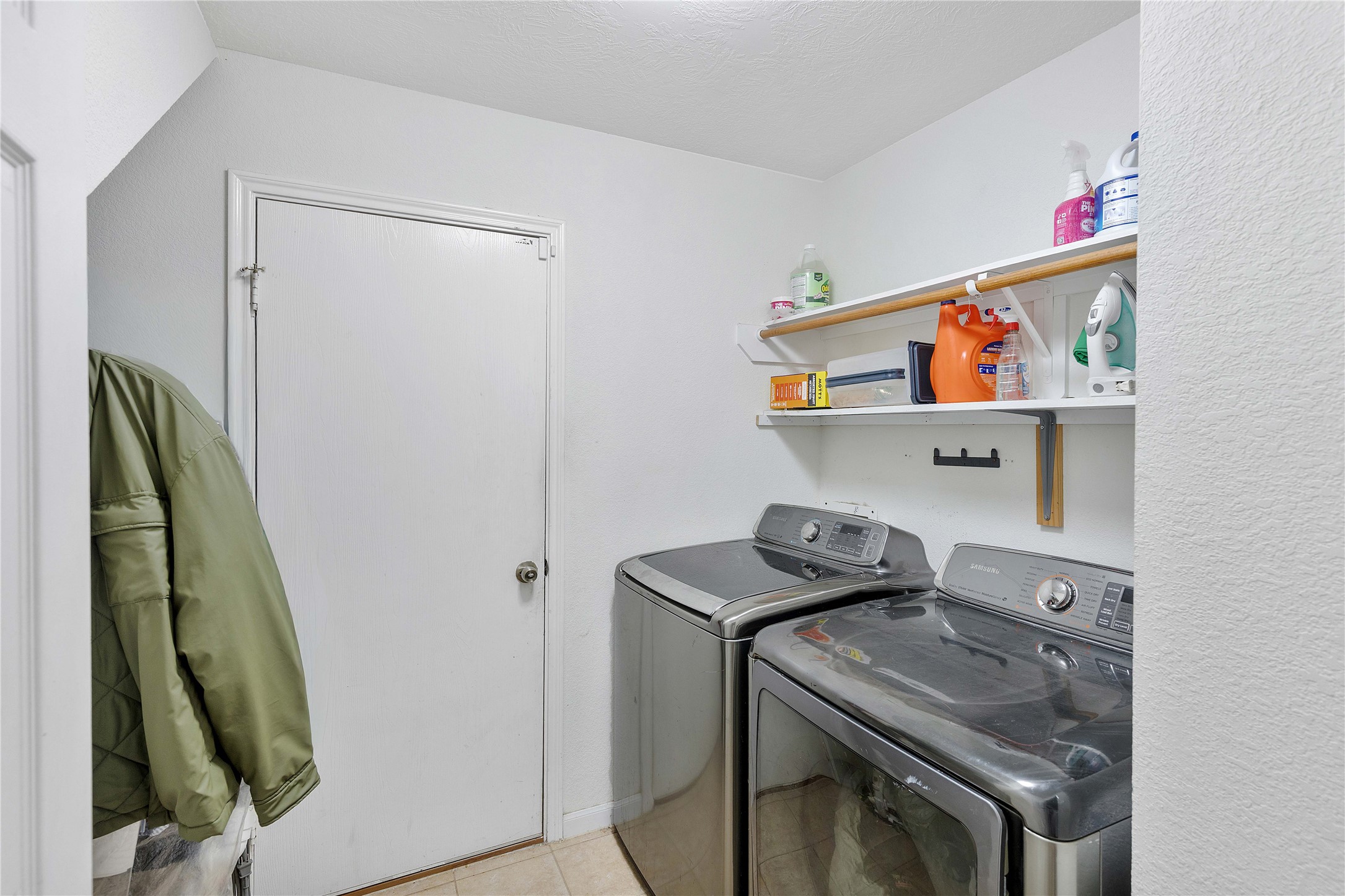 Modern laundry room with sleek appliances, ample shelving for storage, and convenient hanging space.