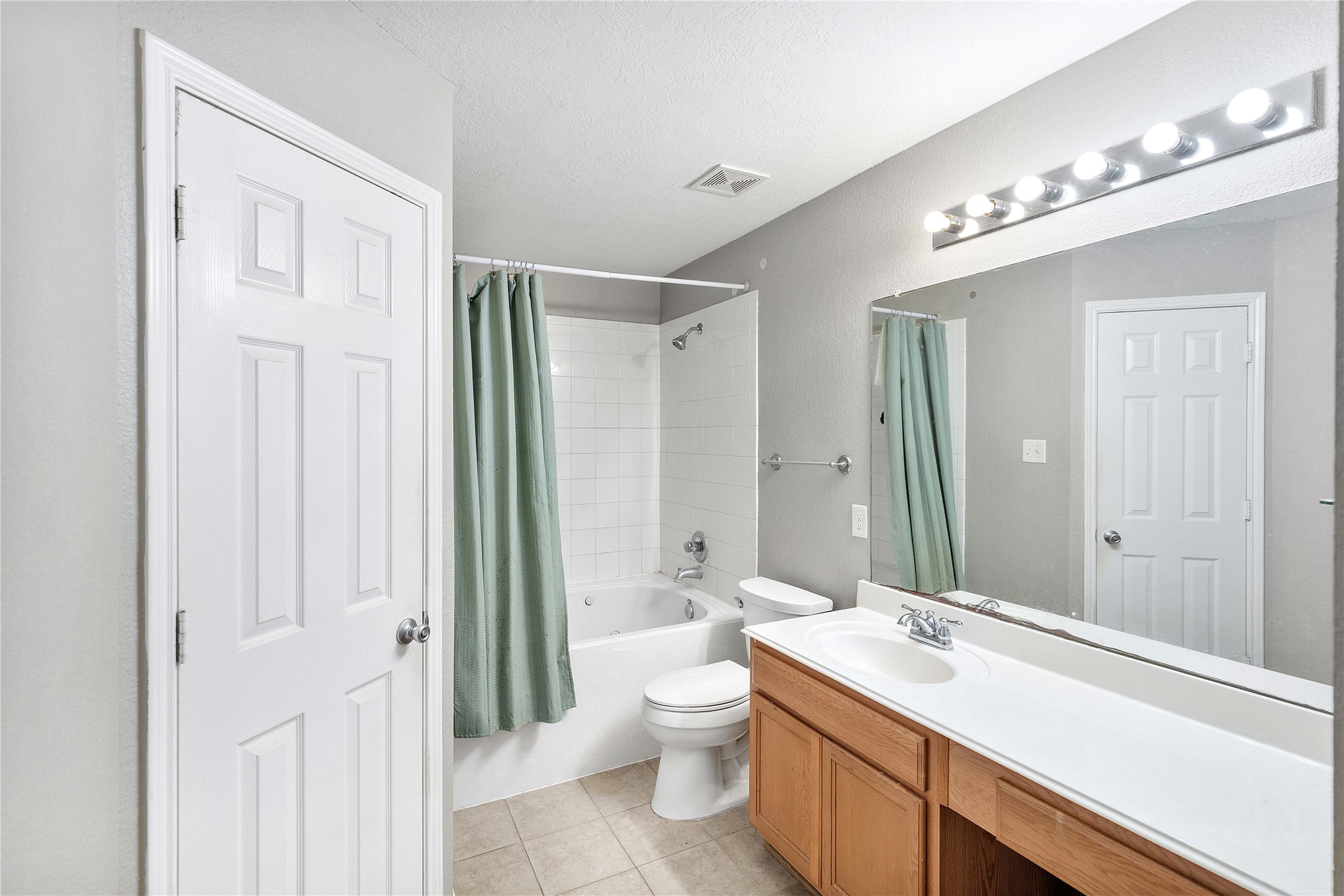 Bright and inviting bathroom featuring a spacious vanity with ample storage, a full bathtub with a shower, and modern lighting for a refreshing ambiance.