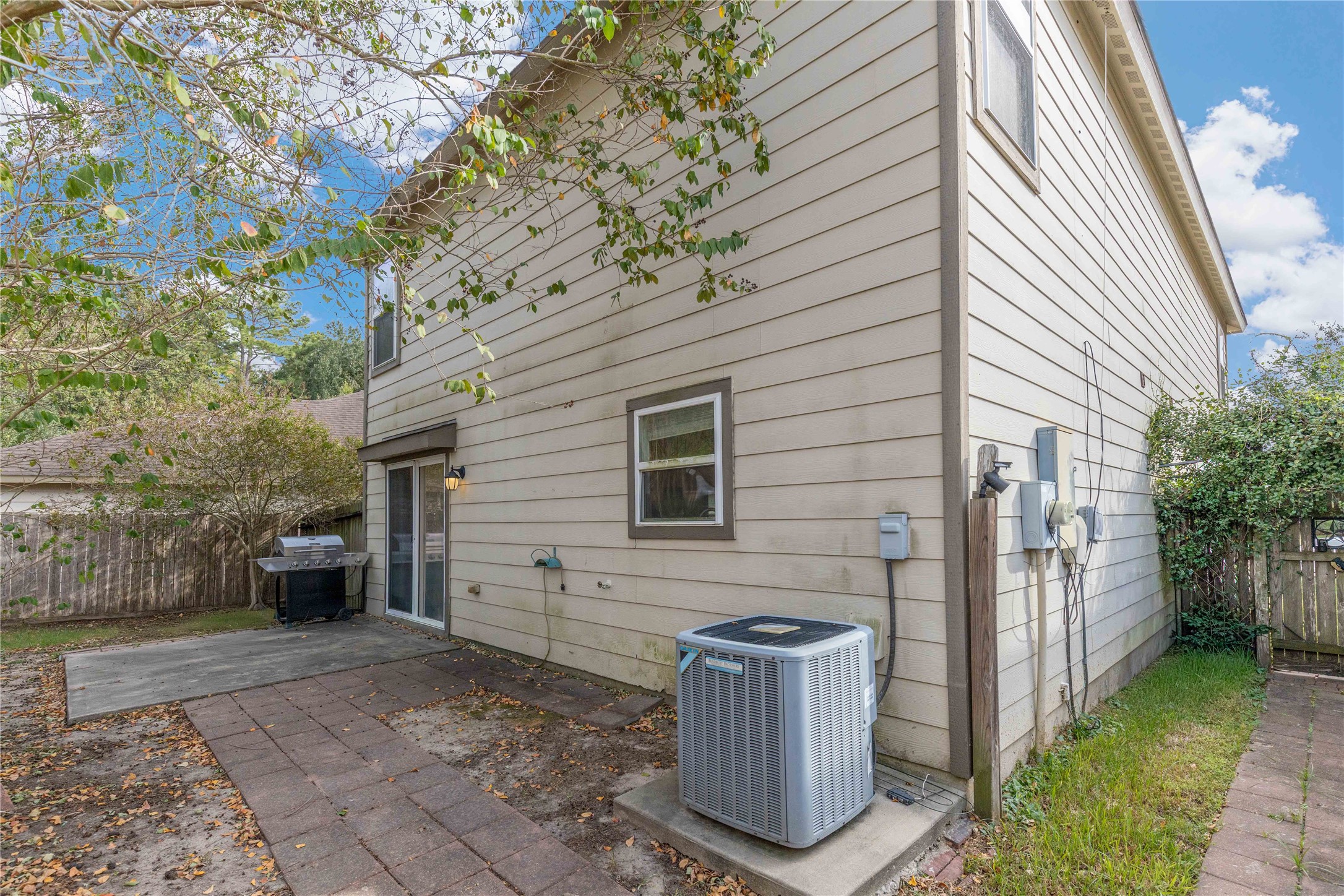 Charming backyard with a spacious patio perfect for outdoor grilling and relaxation, surrounded by mature trees for added privacy.