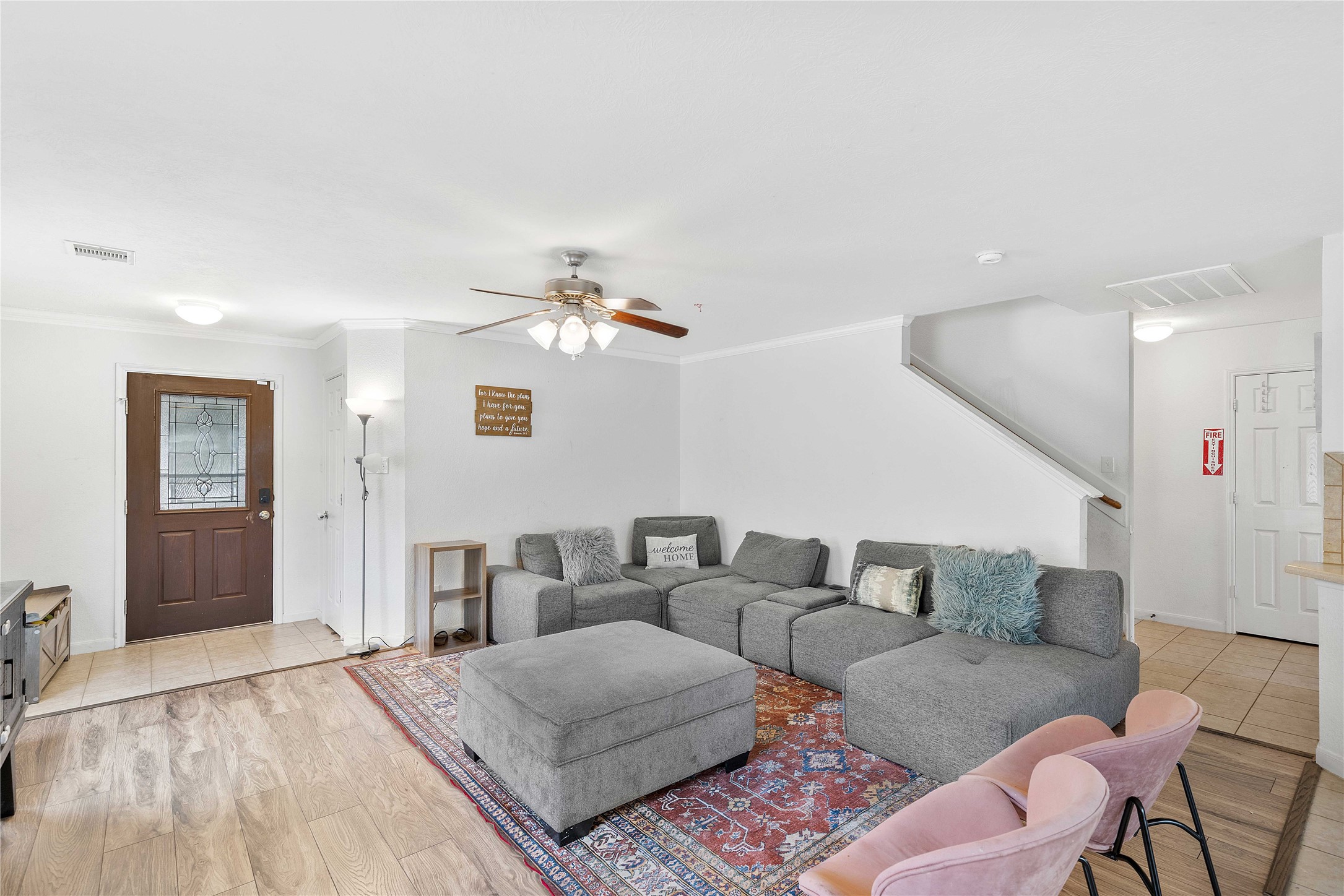 Spacious living area with a large sectional sofa, ceiling fan, and a mix of wood and tile flooring, creating a cozy and inviting atmosphere.