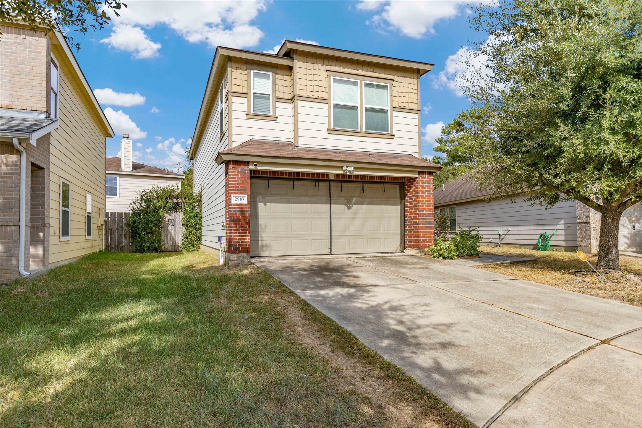 Charming two-story home with a brick and siding exterior, featuring a spacious driveway and attached garage, surrounded by a well-maintained lawn and mature trees.