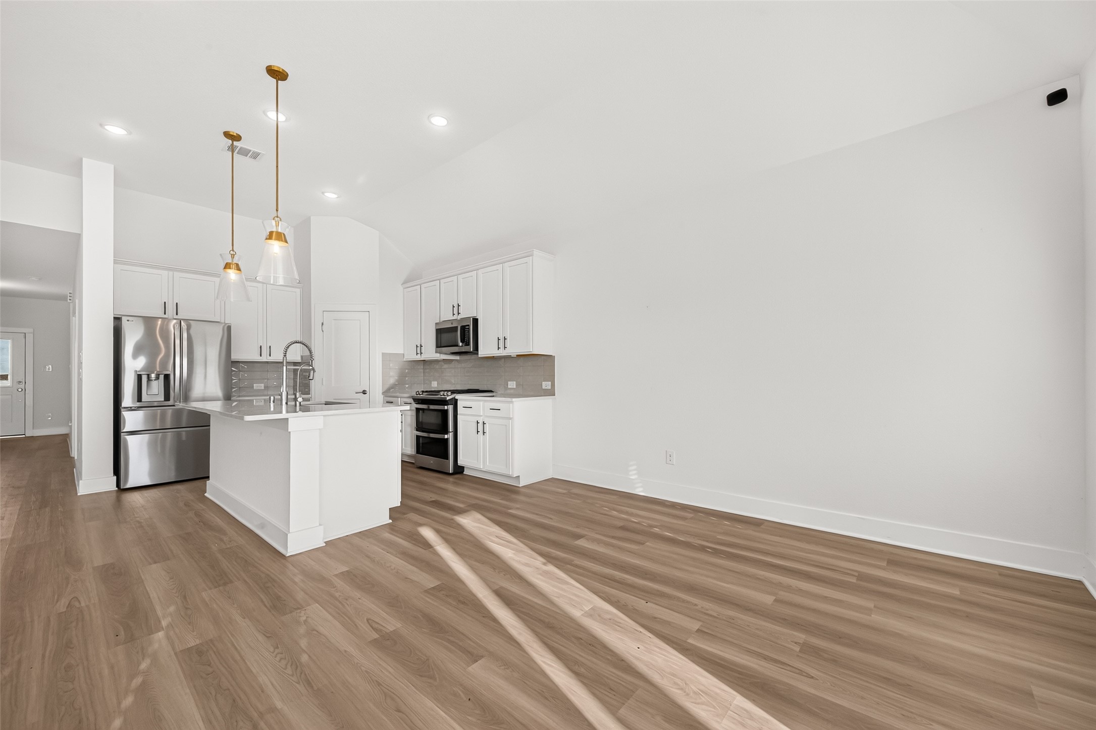 Kitchen with center island, pendant lighting, stainless steel appliances, and white cabinetry.