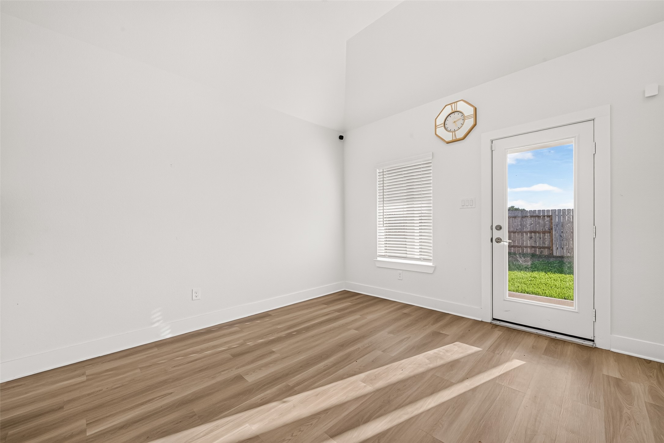 Breakfast area with window, wood-look flooring, and glass door leading to the backyard.