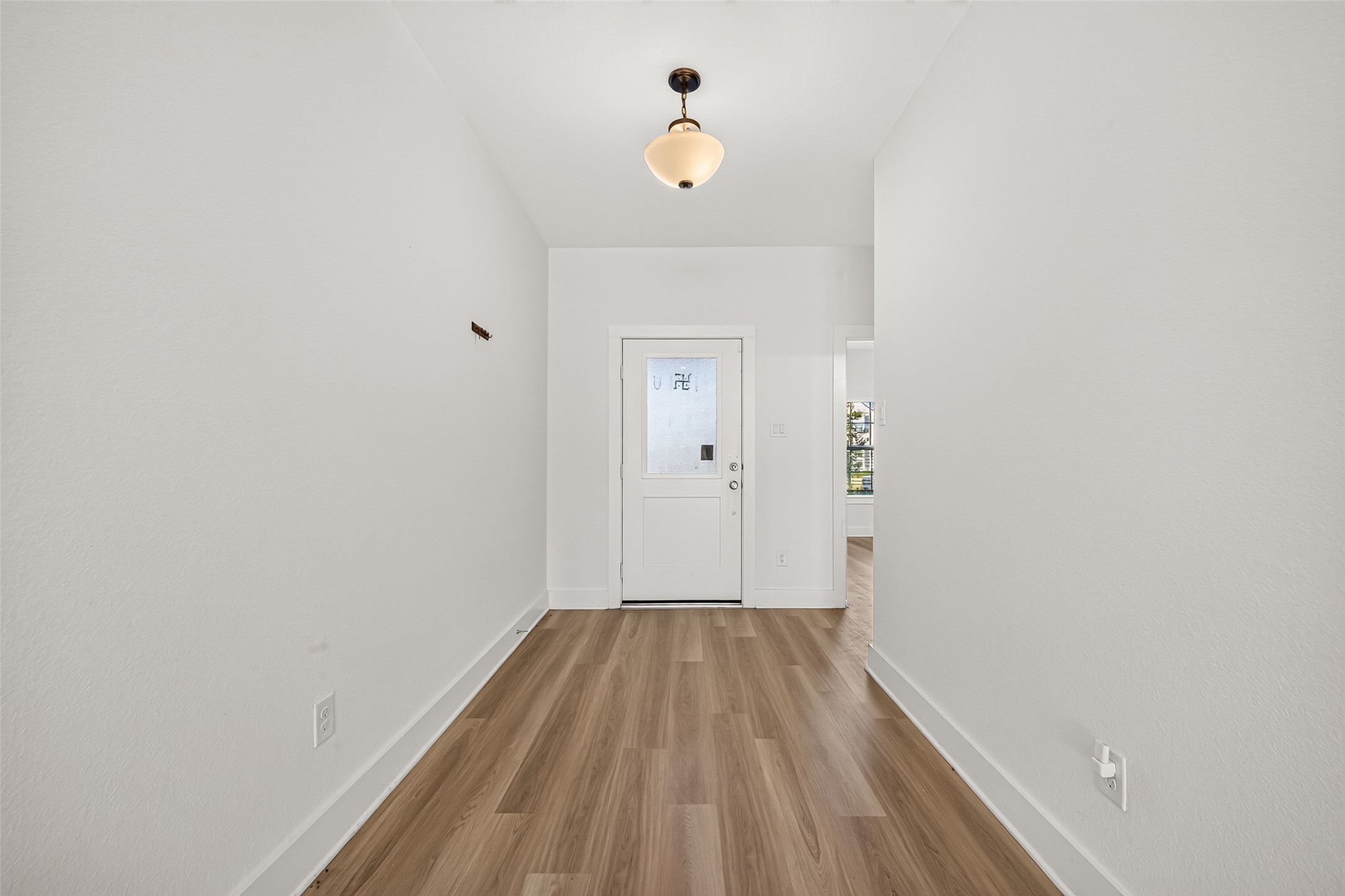 Entry hall with wood-look flooring, pendant light fixture, and neutral paint. Entry hall with wood-look flooring, pendant light fixture, and neutral paint.