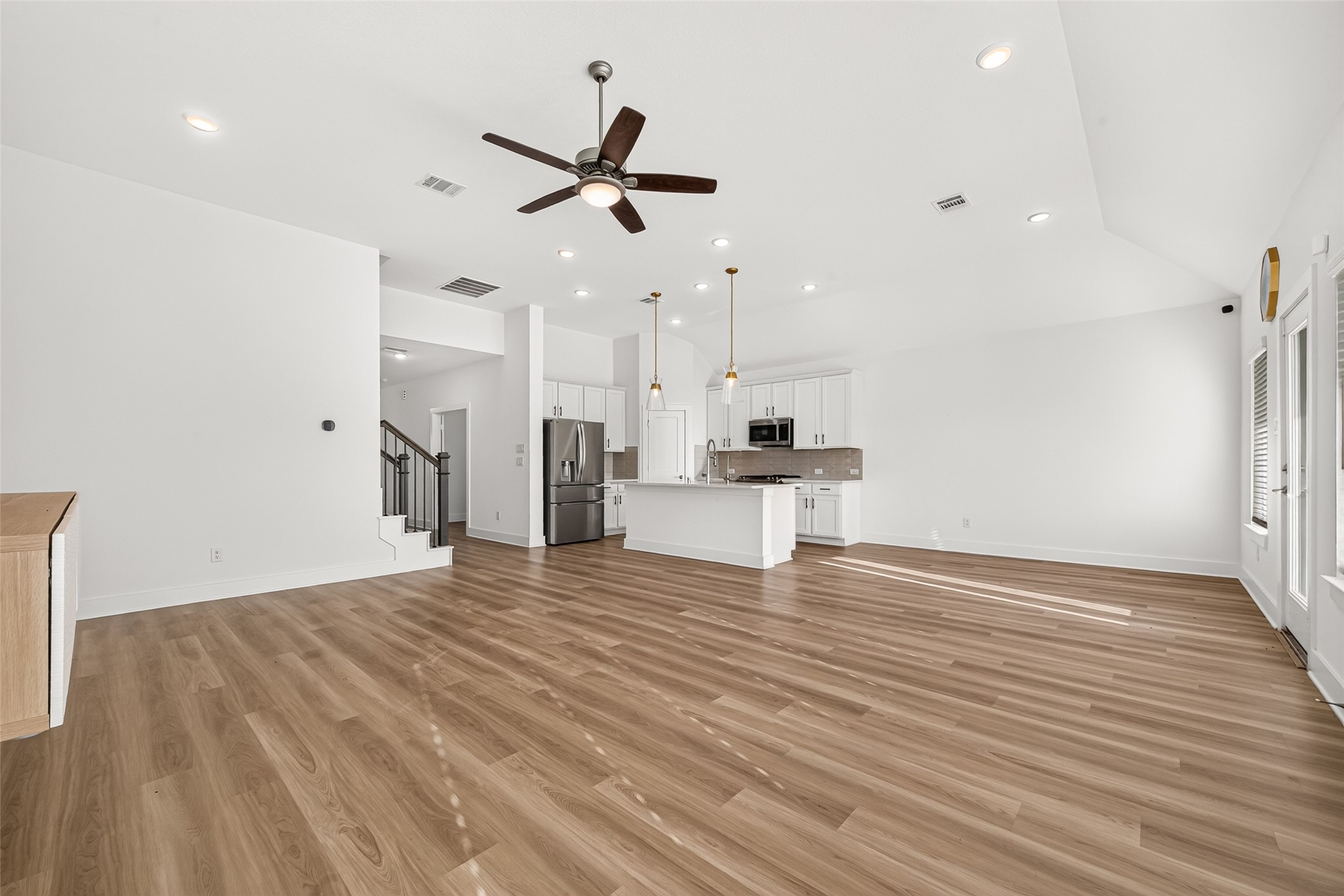 Living room looking toward the kitchen and staircase, showing the open floor plan and high ceilings.