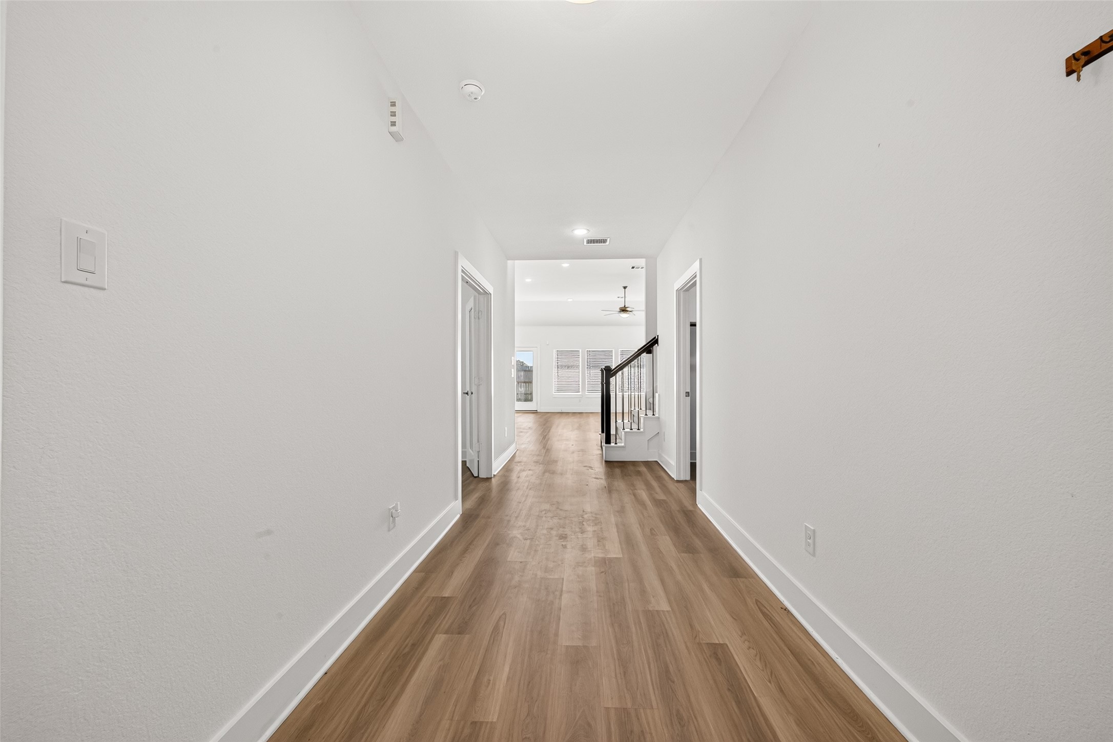 Hallway with wood-look flooring leading from the entry to the open living area and staircase. Hallway with wood-look flooring leading from the entry to the open living area and staircase.