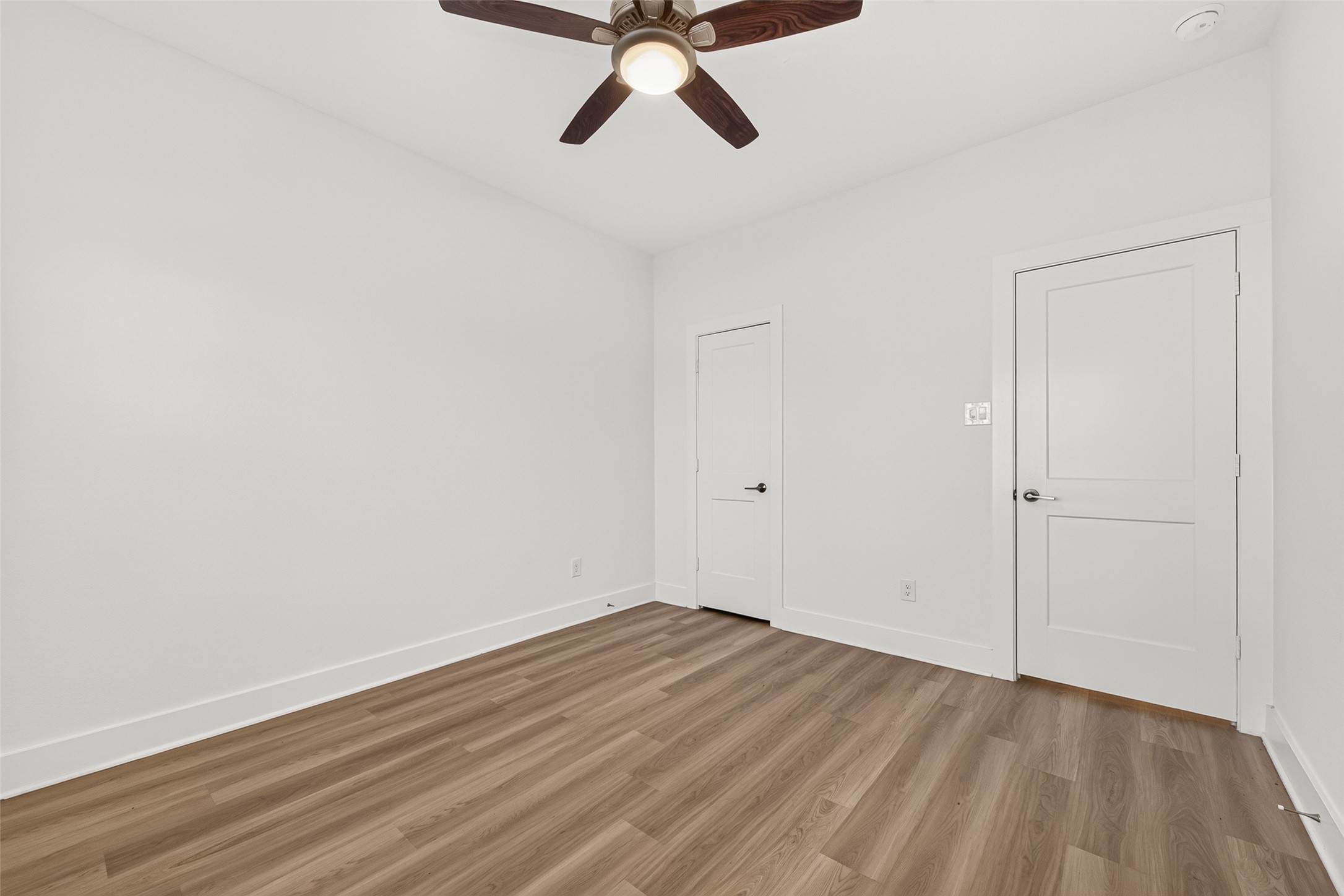Bedroom with ceiling fan, wood-look flooring, and closet.