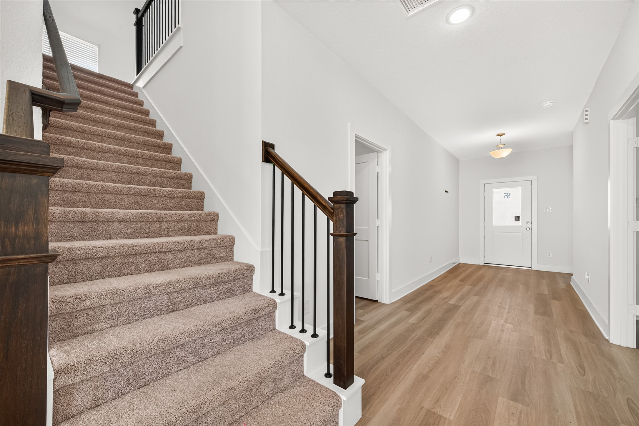 Staircase with carpeted treads, wood handrail, and wrought iron balusters, open to the hallway. Staircase with carpeted treads, wood handrail, and wrought iron balusters, open to the hallway.