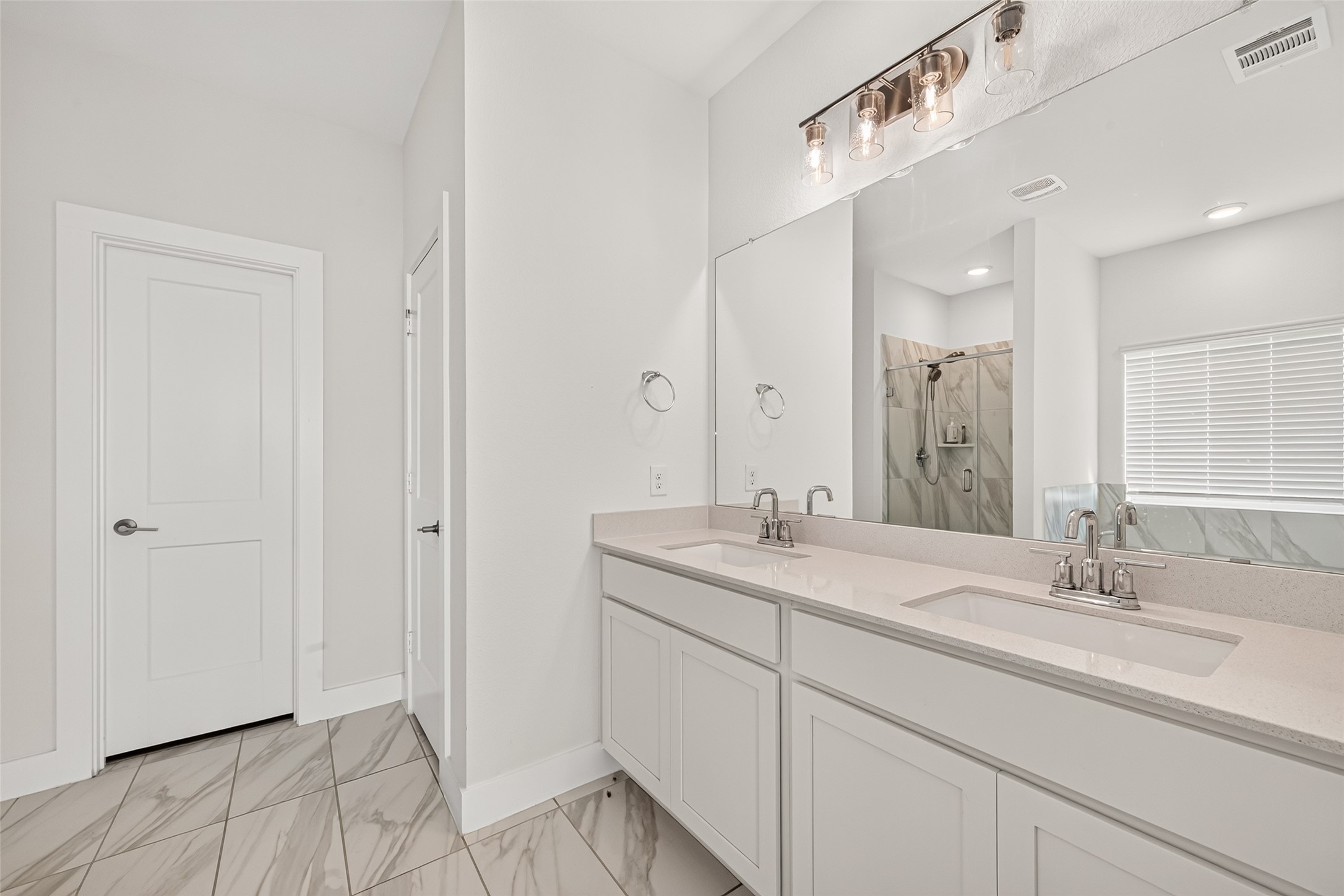 Primary bathroom double vanity with two sinks, large mirror, and vanity lighting.