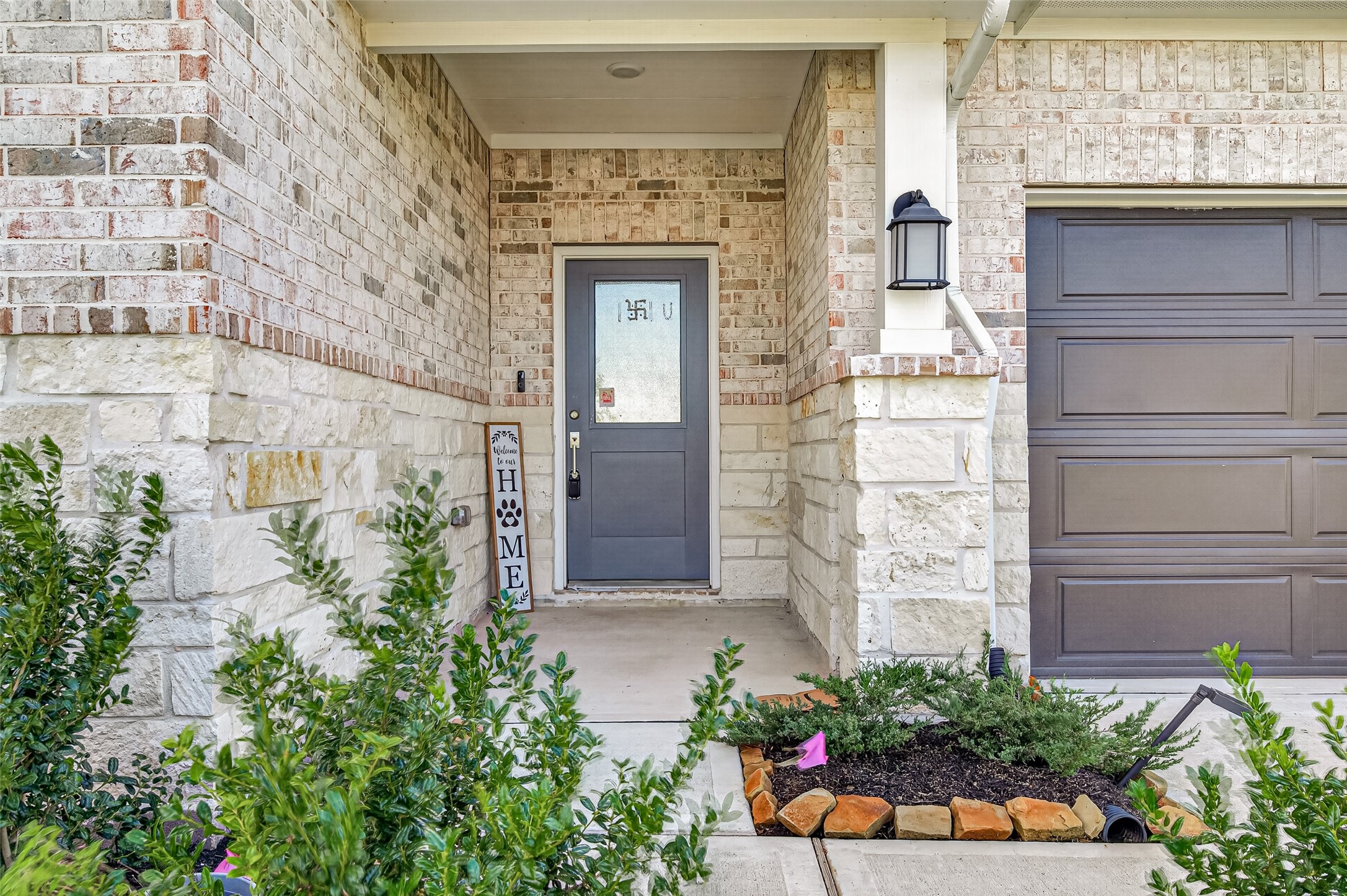 Covered front entry with brick and stone accents, glass-paneled front door, coach light, and landscaped beds. Covered front entry with brick and stone accents, glass-paneled front door, coach light, and landscaped beds.