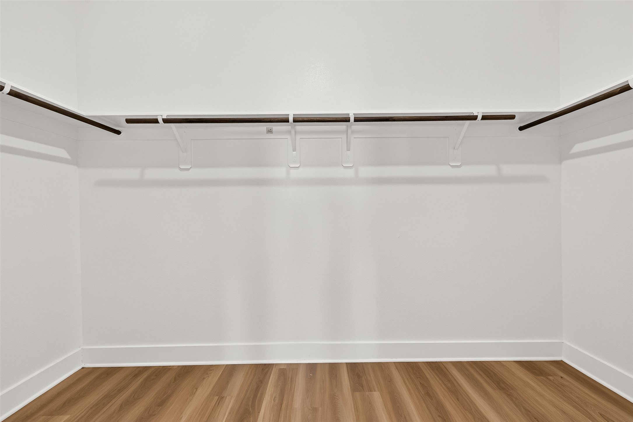 Walk-in closet with hanging rods and shelving on multiple walls.
