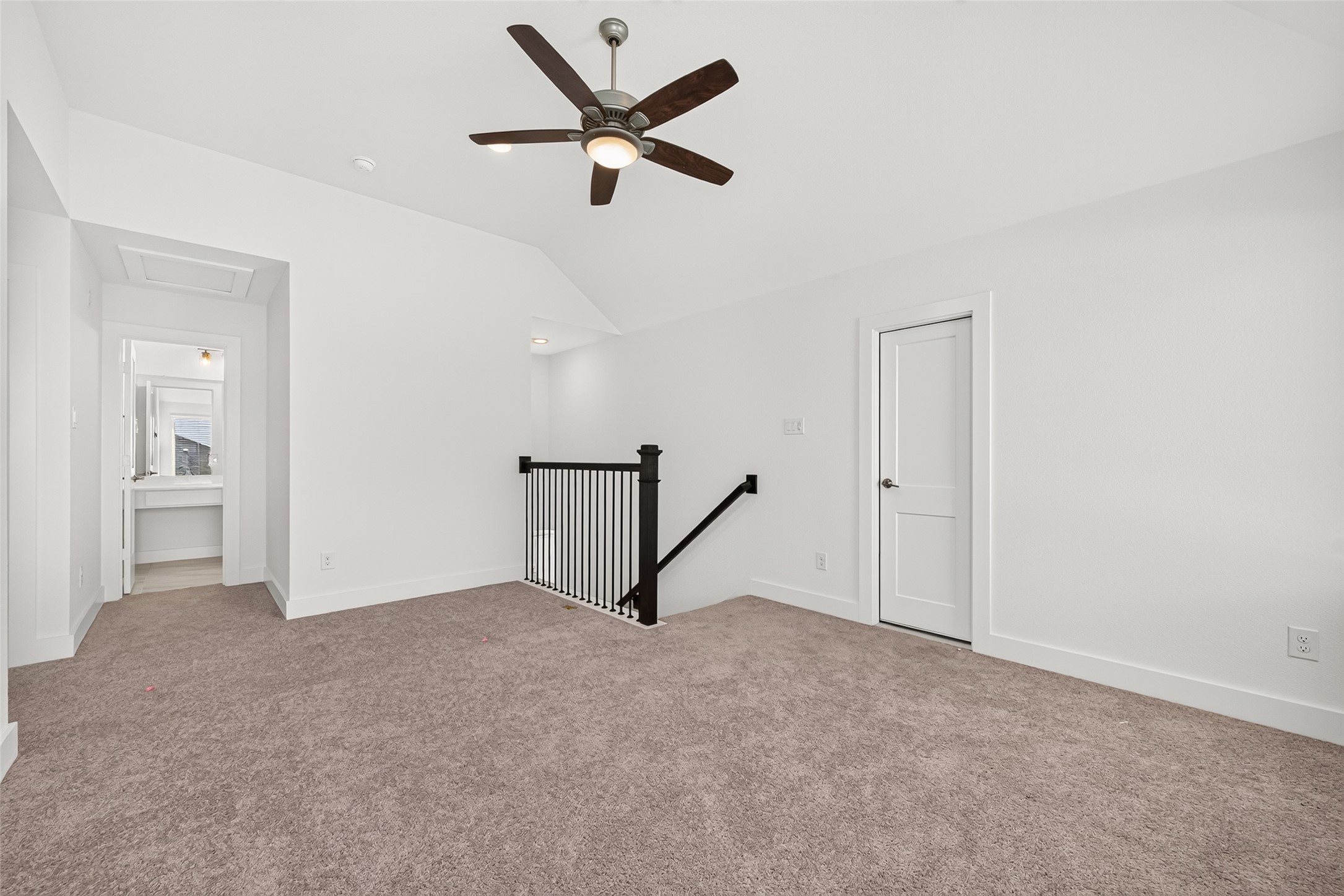 Upstairs loft with carpet and ceiling fan, open to the hallway and secondary bathroom.
