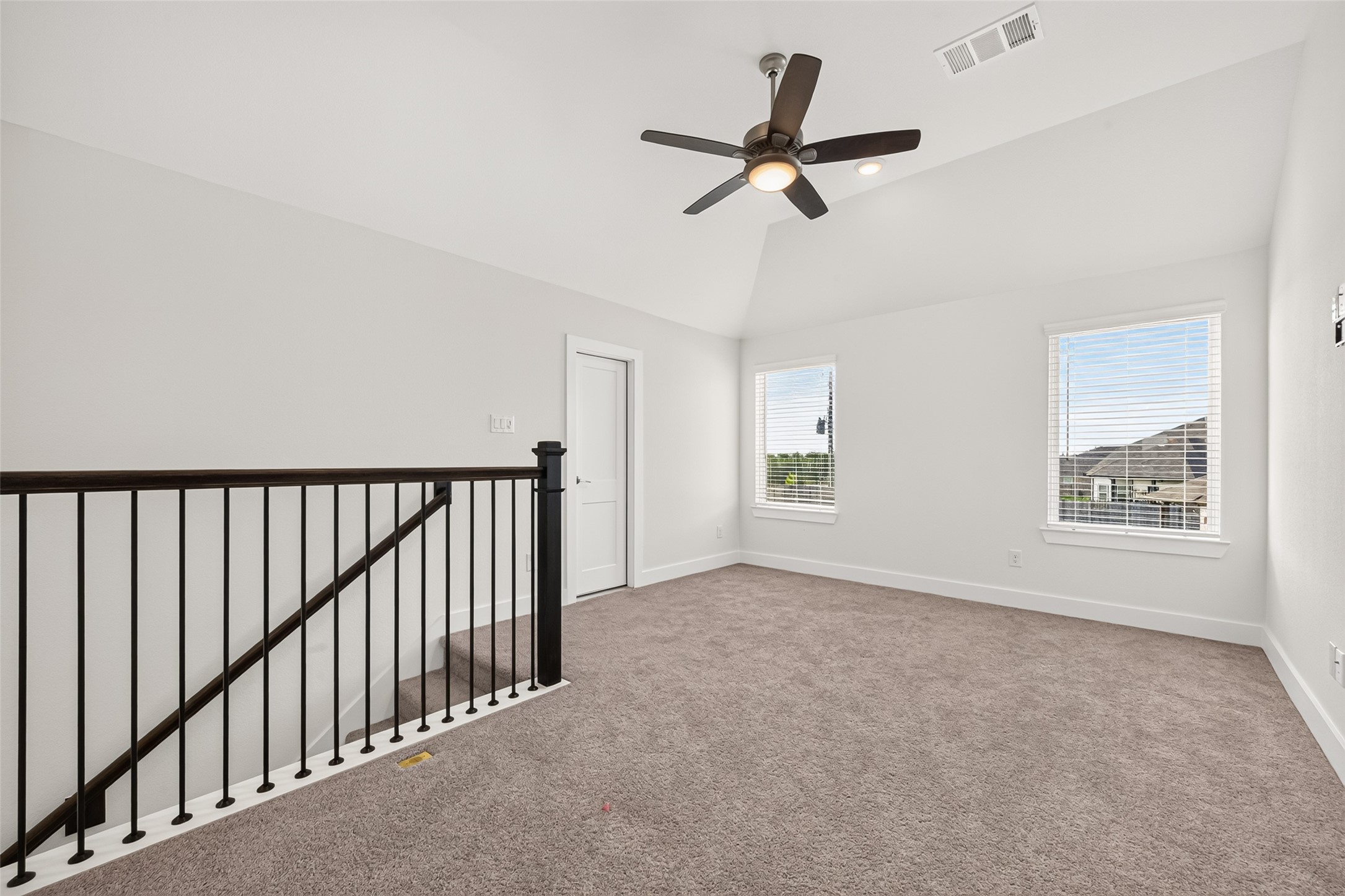Upstairs loft with iron railing overlooking the staircase and two windows.