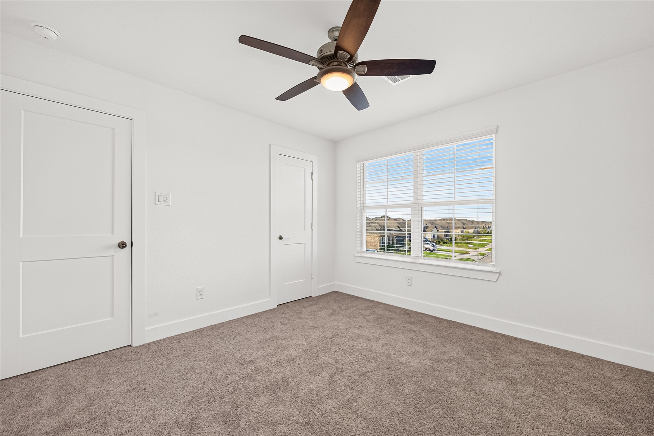 Upstairs bedroom with carpet, ceiling fan, window, and closet.