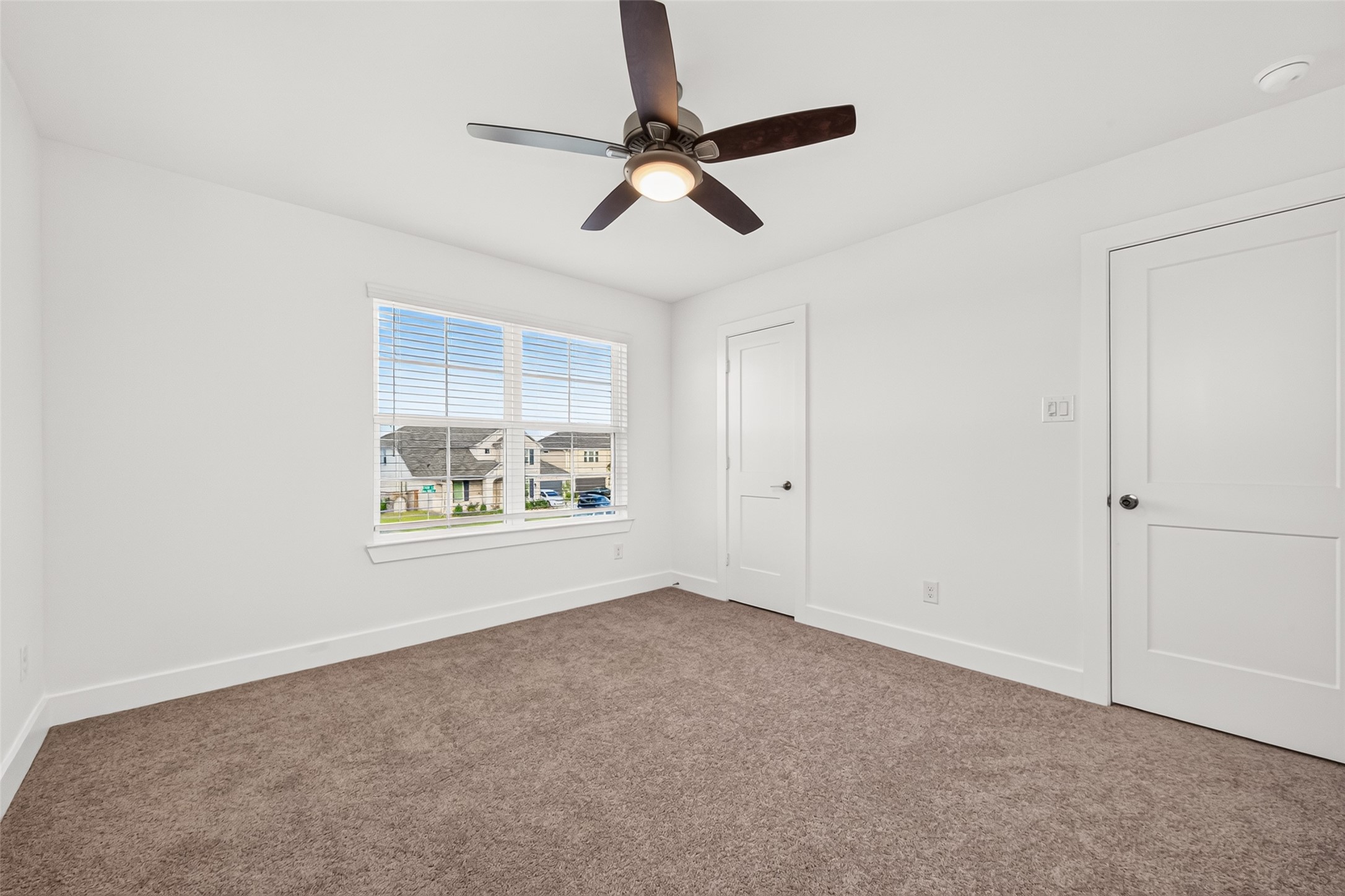 Upstairs bedroom with carpet, ceiling fan, window, and closet.