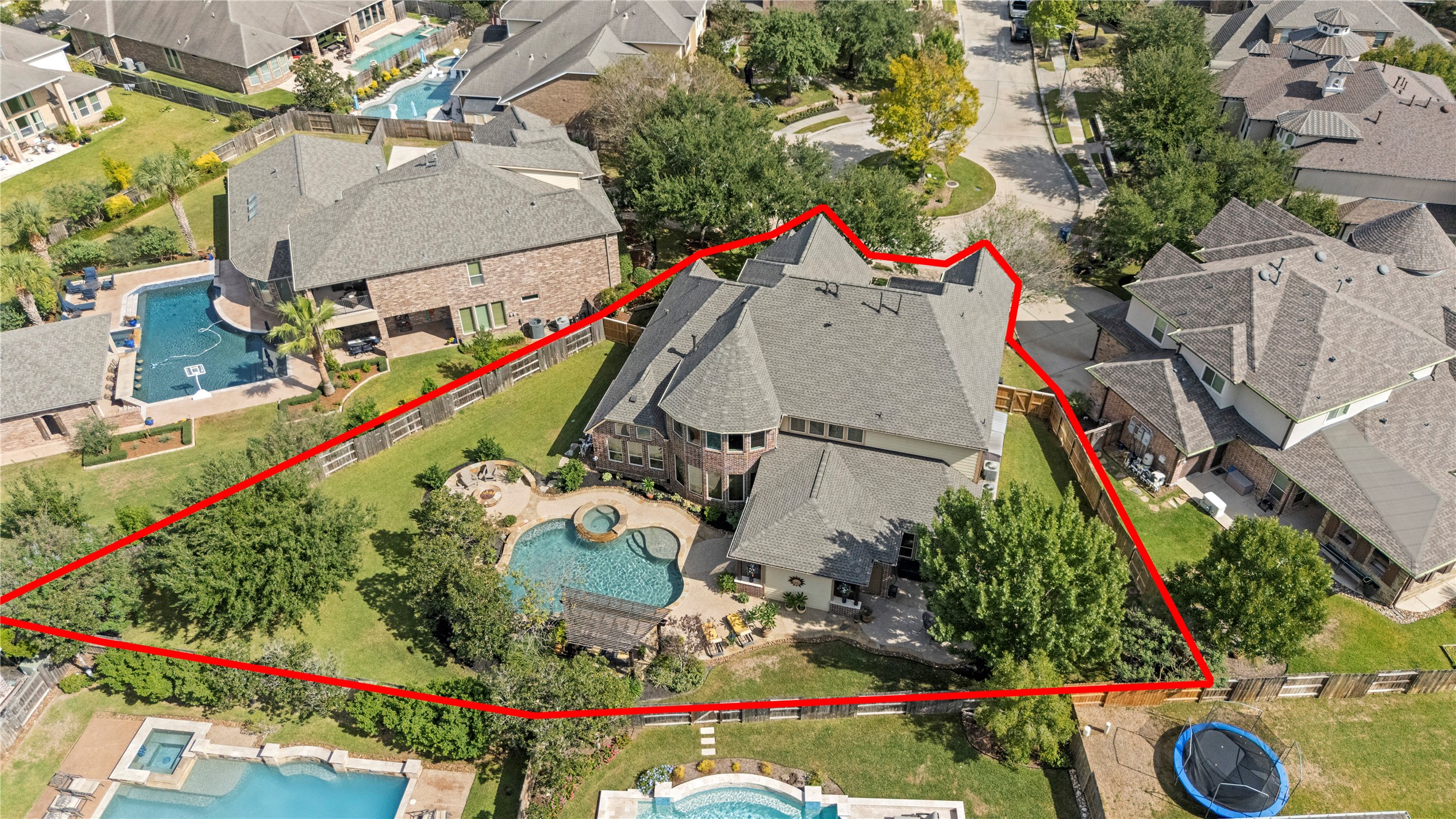 Aerial view outlining the property's lot and showcasing the spacious backyard, swimming pool, and outdoor living areas.