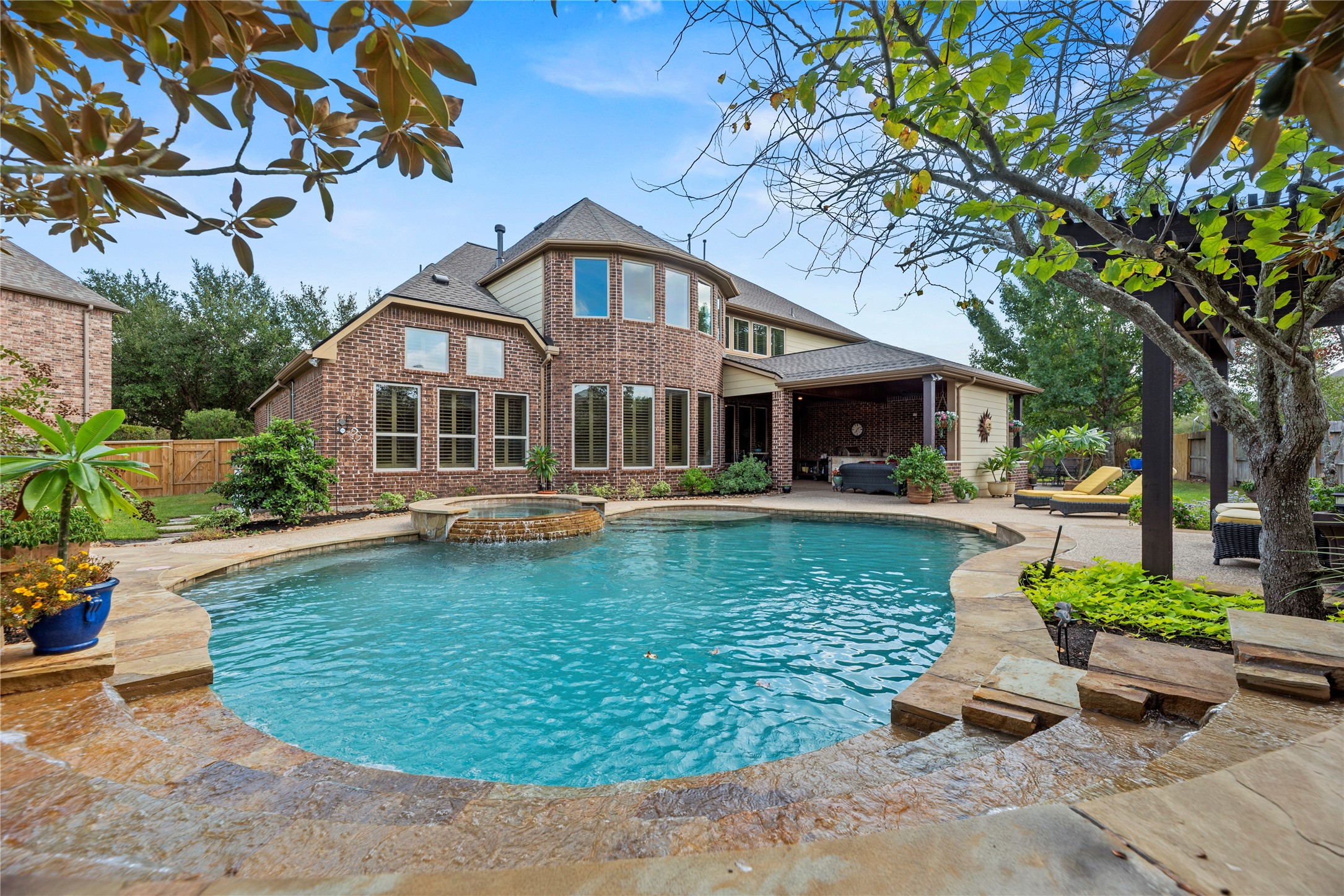 Stunning view of the swimming pool with the home's beautiful brick exterior in the background.