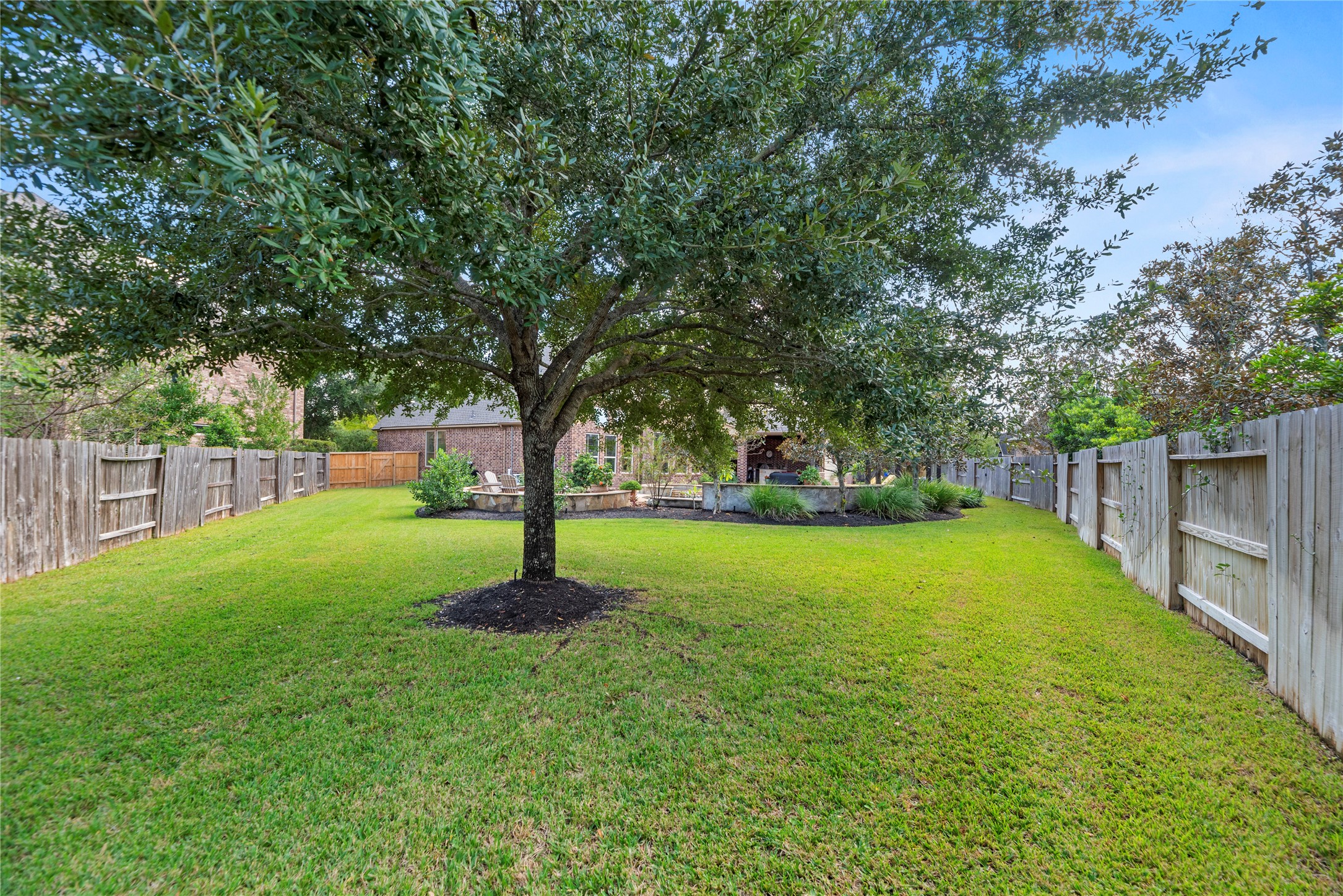 Expansive backyard with lush green grass, mature shade trees, and plenty of open space for outdoor activities.