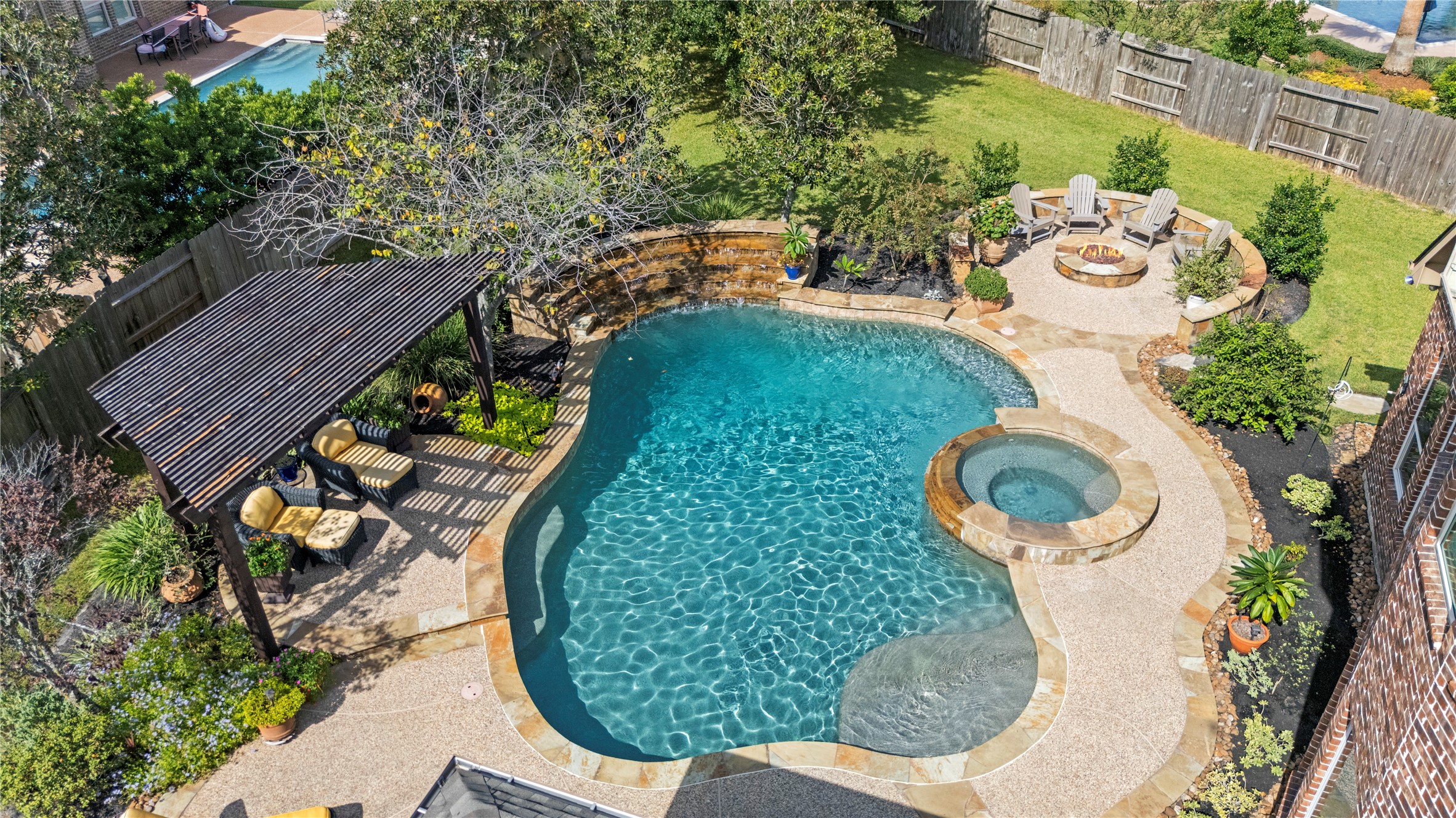 Stunning aerial view of the backyard oasis, highlighting the sparkling swimming pool, spacious patio, and covered outdoor entertaining area.