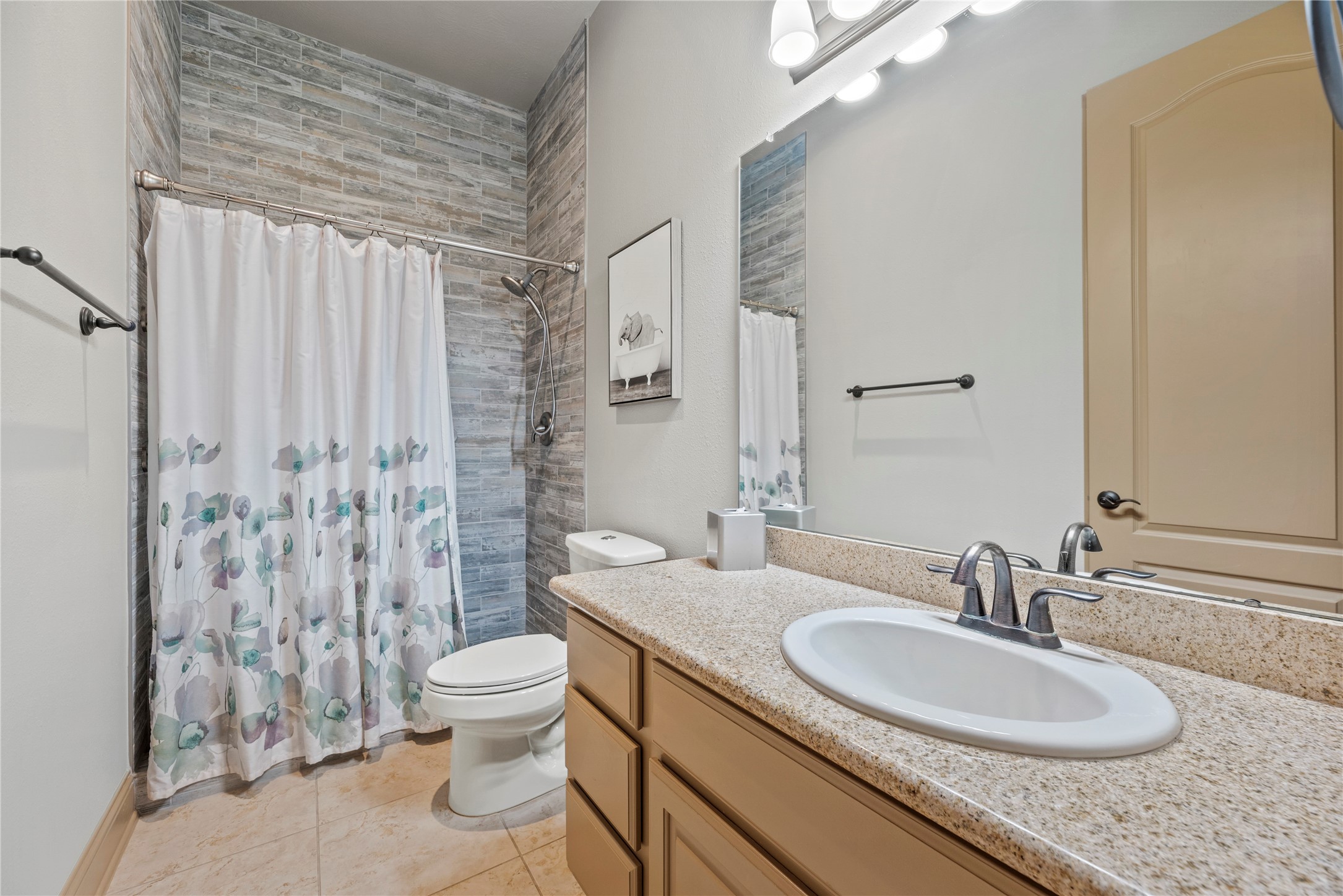 Secondary downstairs bathroom featuring a spacious vanity, decorative tile accents, and a shower.