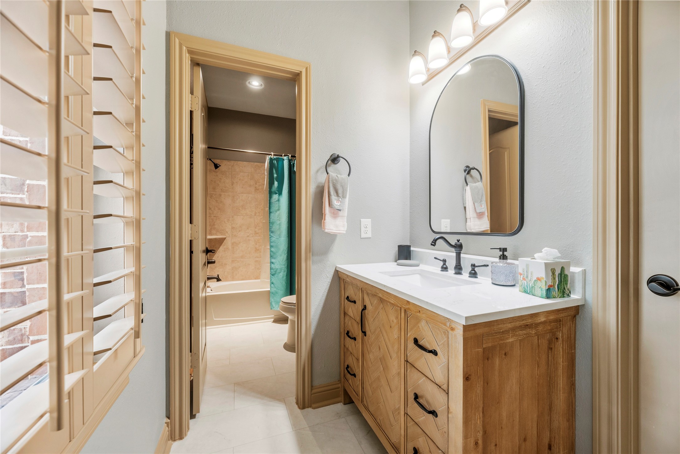 Bathroom with a beautiful vanity, decorative mirror, and warm finishes.
