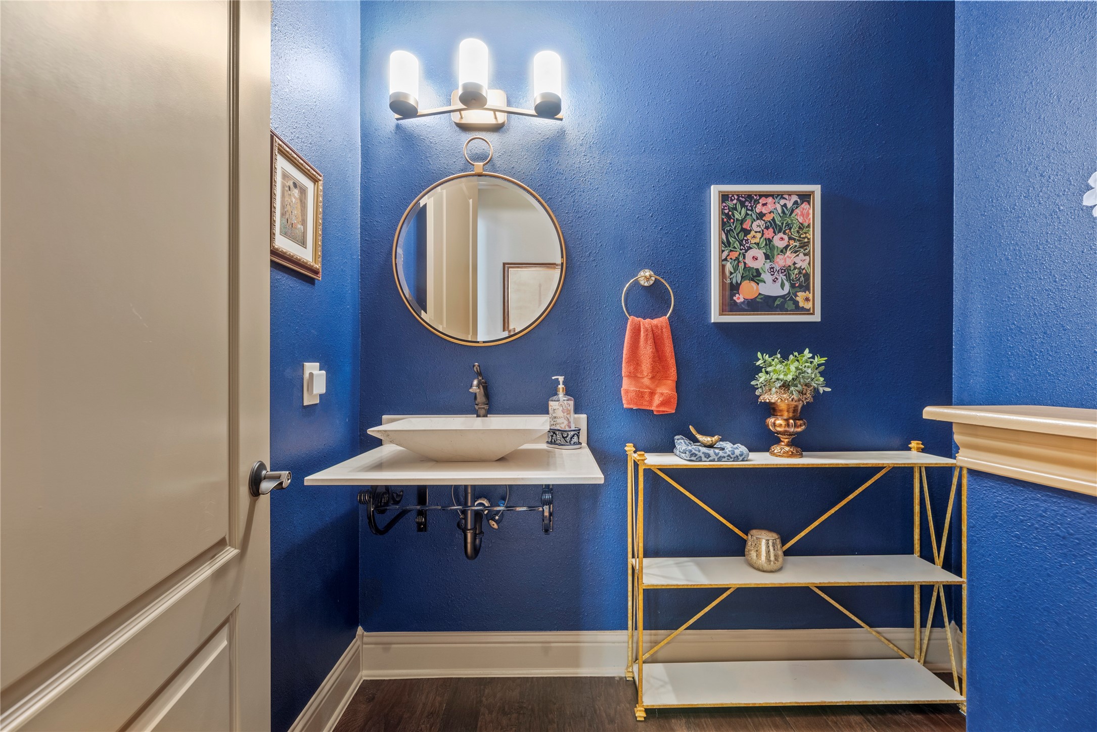 Stylish half bathroom featuring bold blue walls, a spacious vanity, and unique decorative details.