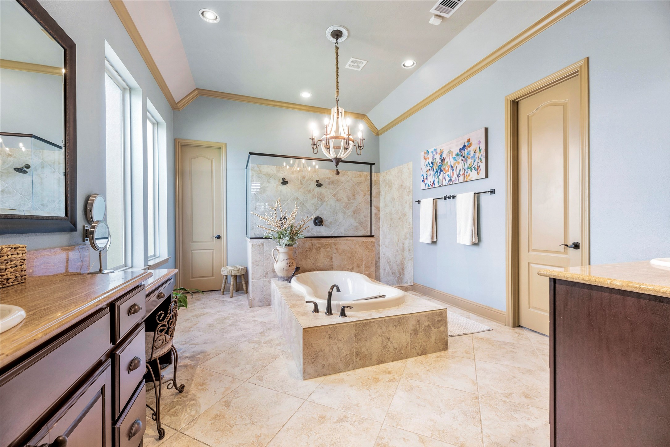 Luxurious primary bathroom featuring a spacious soaking tub, elegant finishes, and a beautiful chandelier.