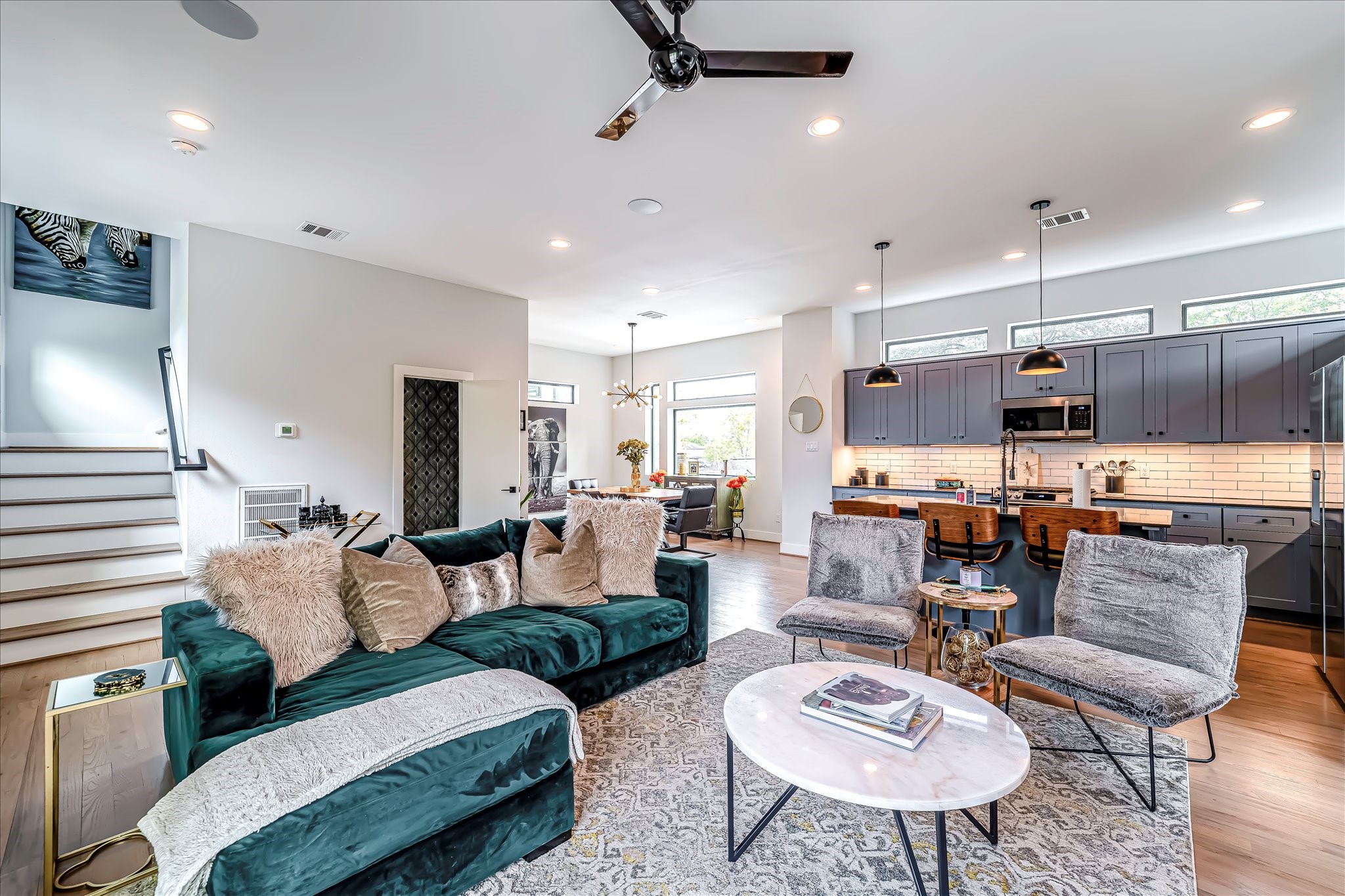 Bright open-concept living space with abundant natural light, designer finishes, and elegant hardwood floors throughout. Photos reflect previous furnishings. Home is currently vacant. Furnishings shown are for illustrative purposes only.
