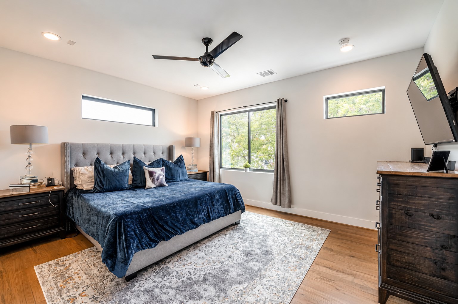 Spacious primary retreat with oversized dimensions, abundant natural light, and elegant hardwood flooring. Photos reflect previous furnishings. Home is currently vacant. Furnishings shown are for illustrative purposes only.