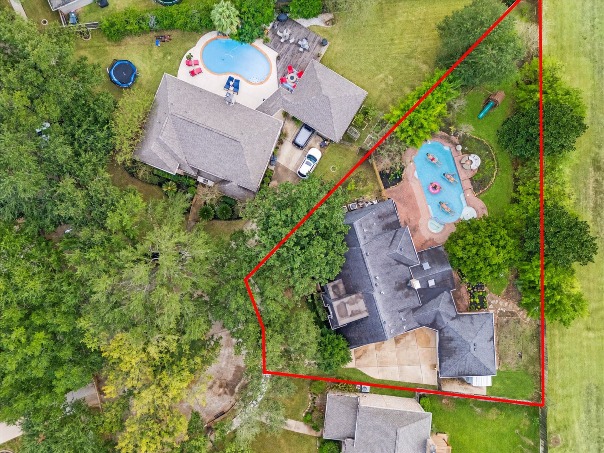 This aerial highlights the home's impressively deep, tree-canopied lot, showcasing the main residence and its sprawling, fenced outdoor entertainment area with a large in-ground pool. This aerial highlights the home's impressively deep, tree-canopied lot, showcasing the main residence and its sprawling, fenced outdoor entertainment area with a large in-ground pool.