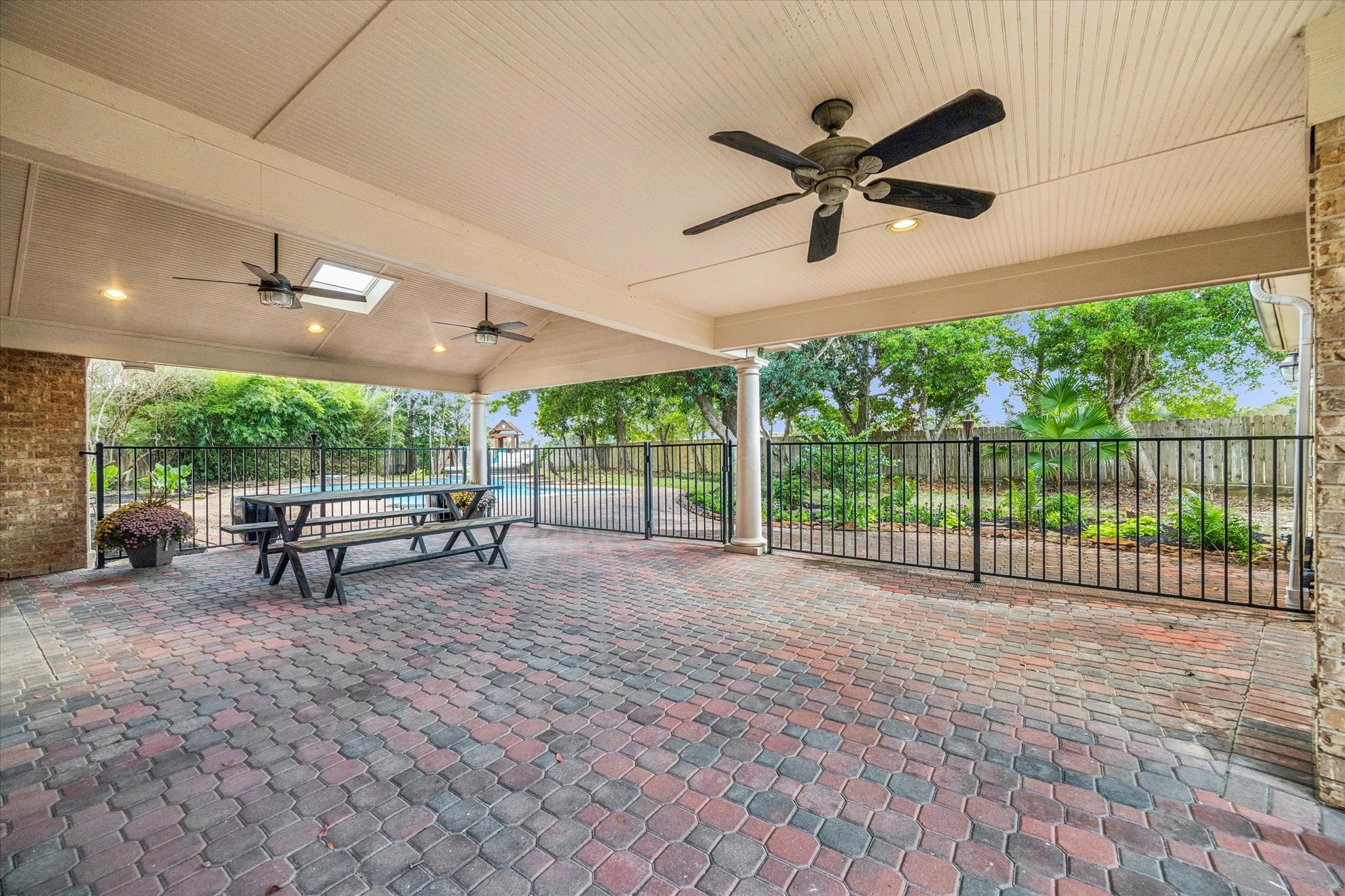 A view of the large covered patio, which features a new child-proof fence and ceiling fans, leading out to the spacious backyard.