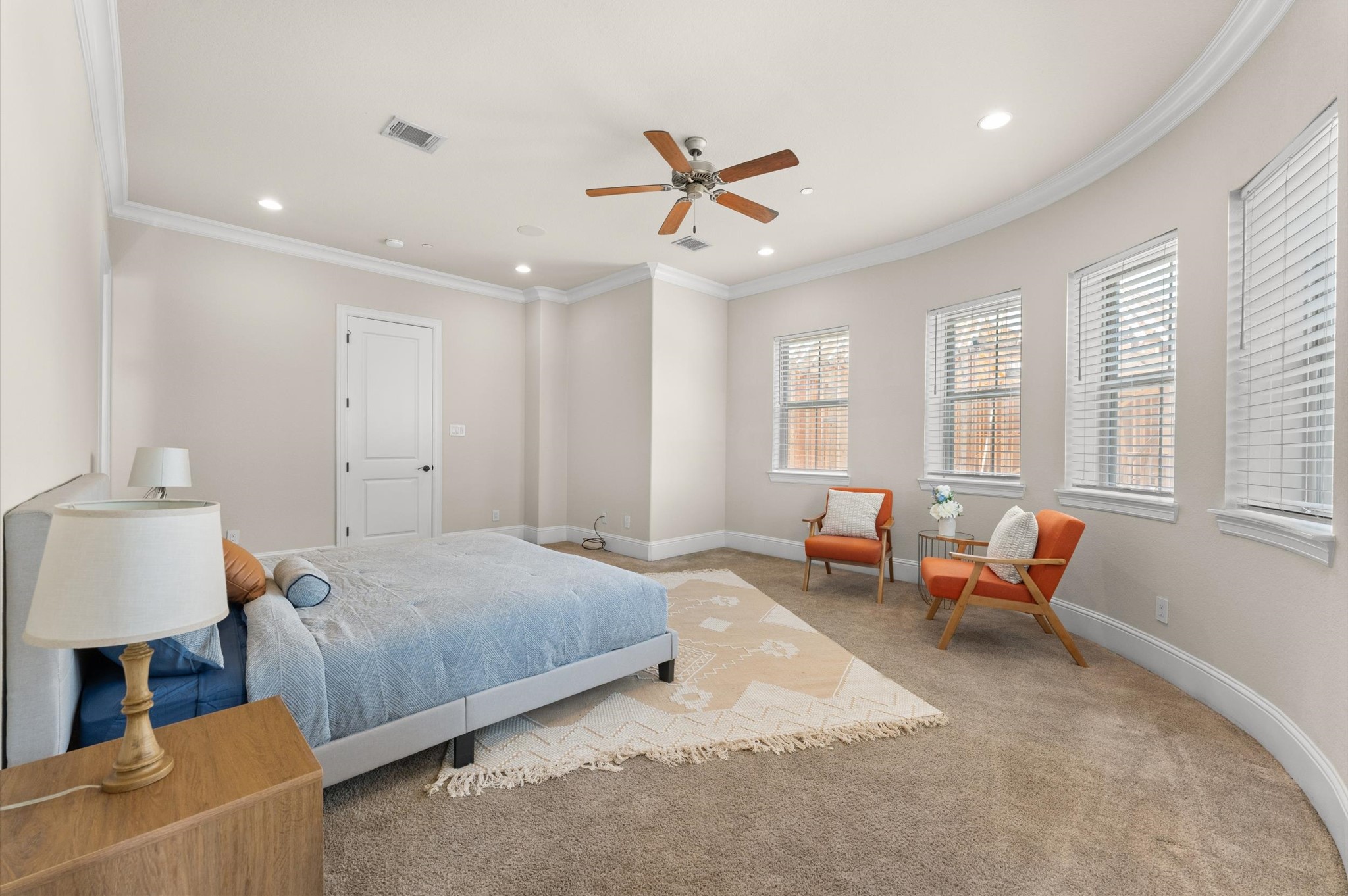 Primary bedroom featuring a curved window and an ample sitting area.