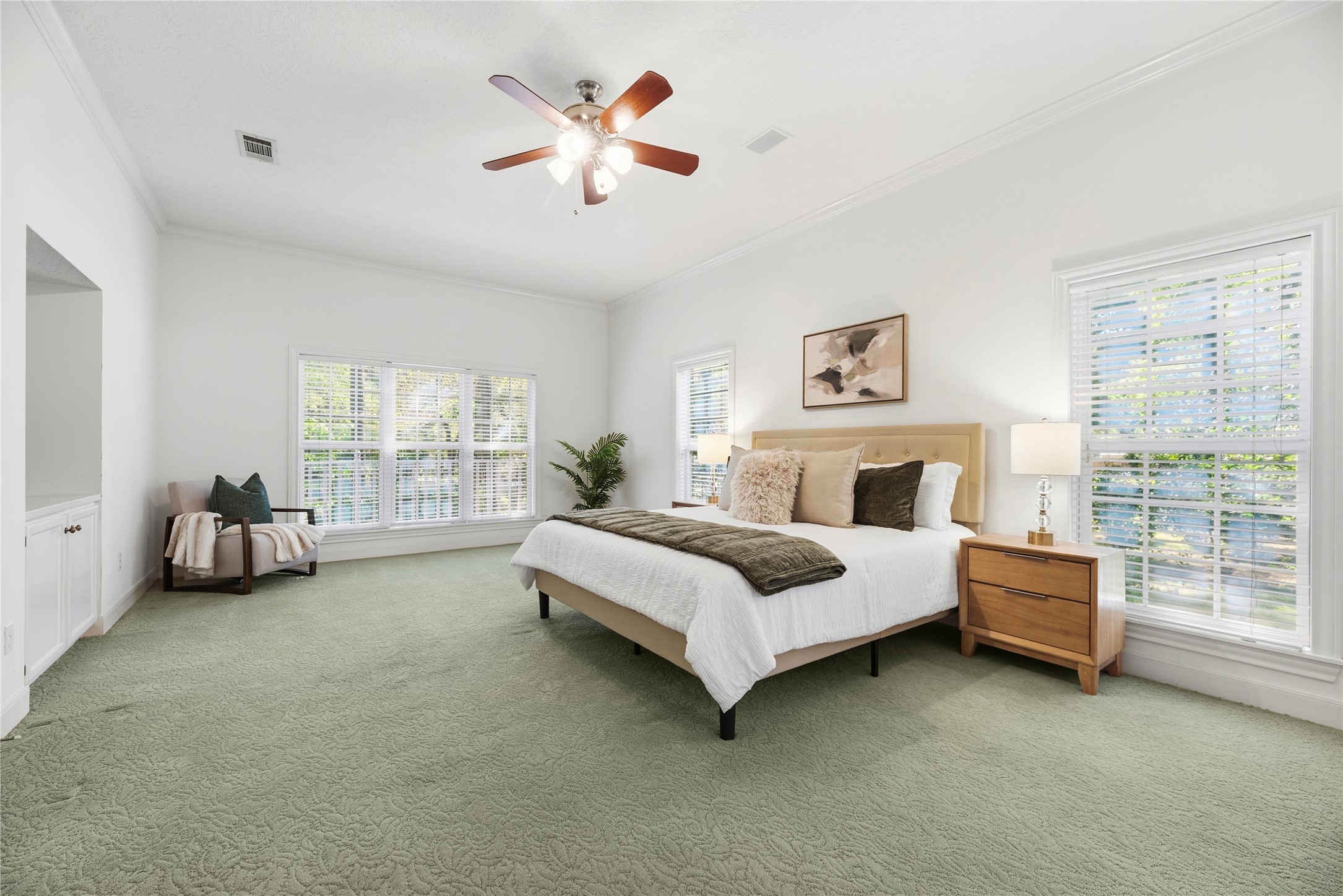 Spacious primary suite filled with natural light, featuring high ceilings, multiple oversized windows, and plenty of room for a sitting area.