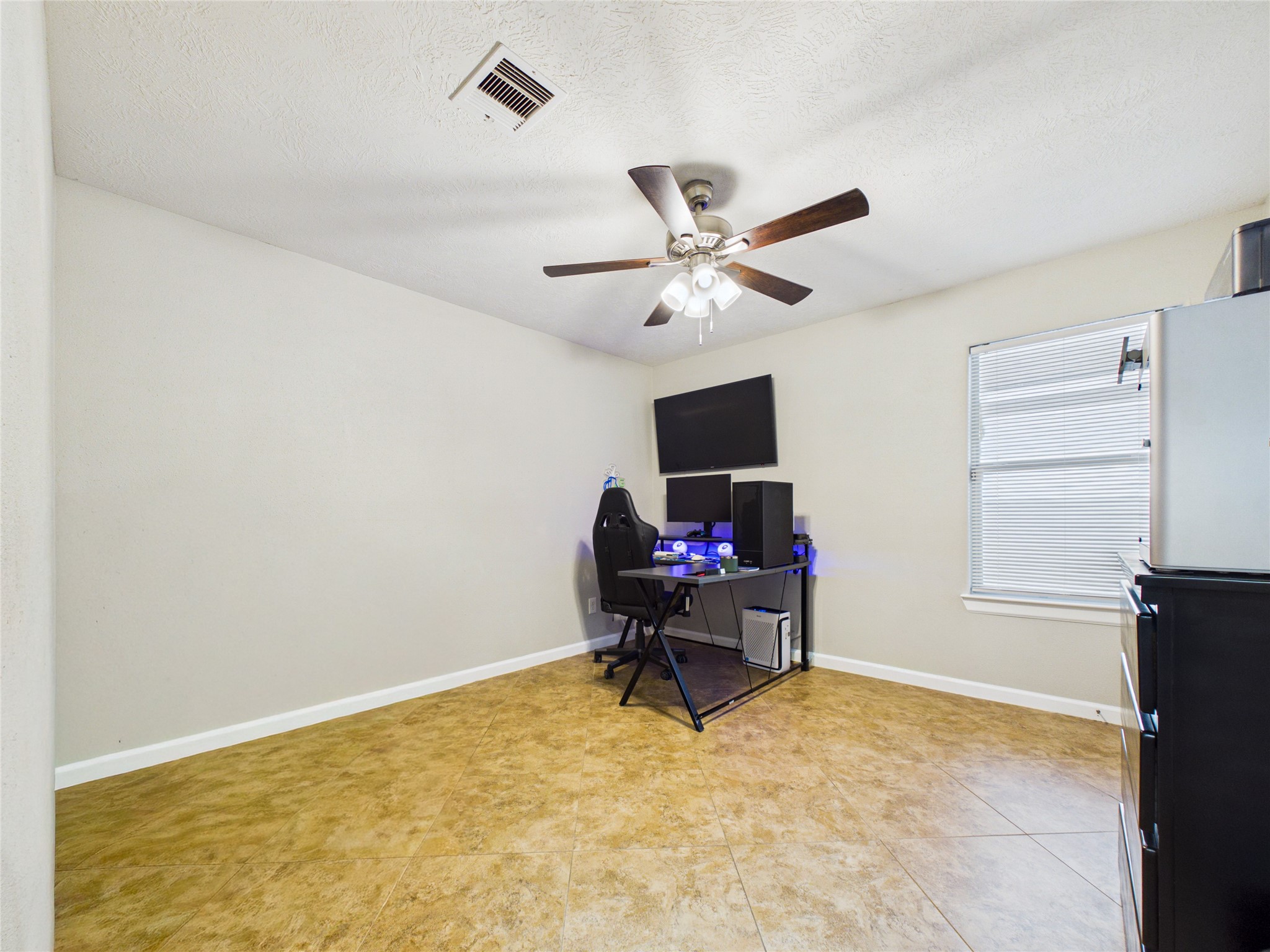 Spacious 2nd bedroom with neutral walls, tile flooring, and a ceiling fan.