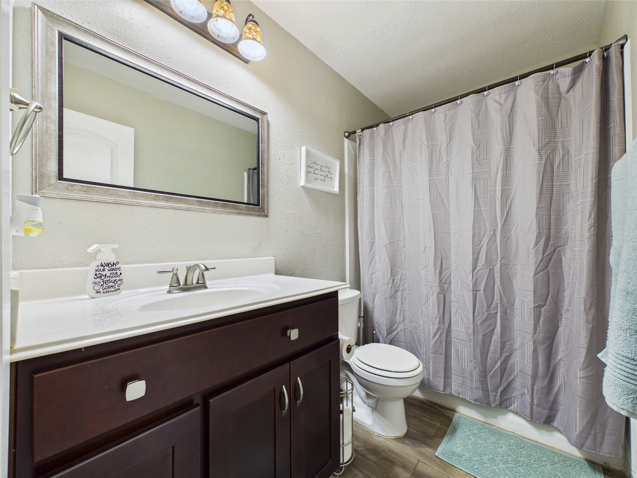 This secondary bathroom features dark wood cabinetry, a modern countertop, bath/shower combo.