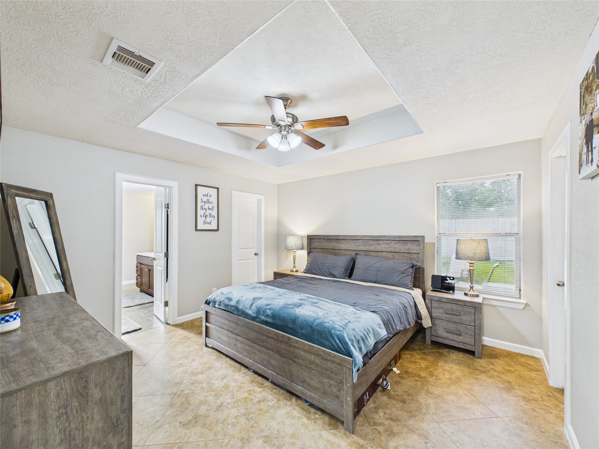 Beautiful primary bedroom with a stunning tray ceiling and spacious his-and-hers walk-in closets.