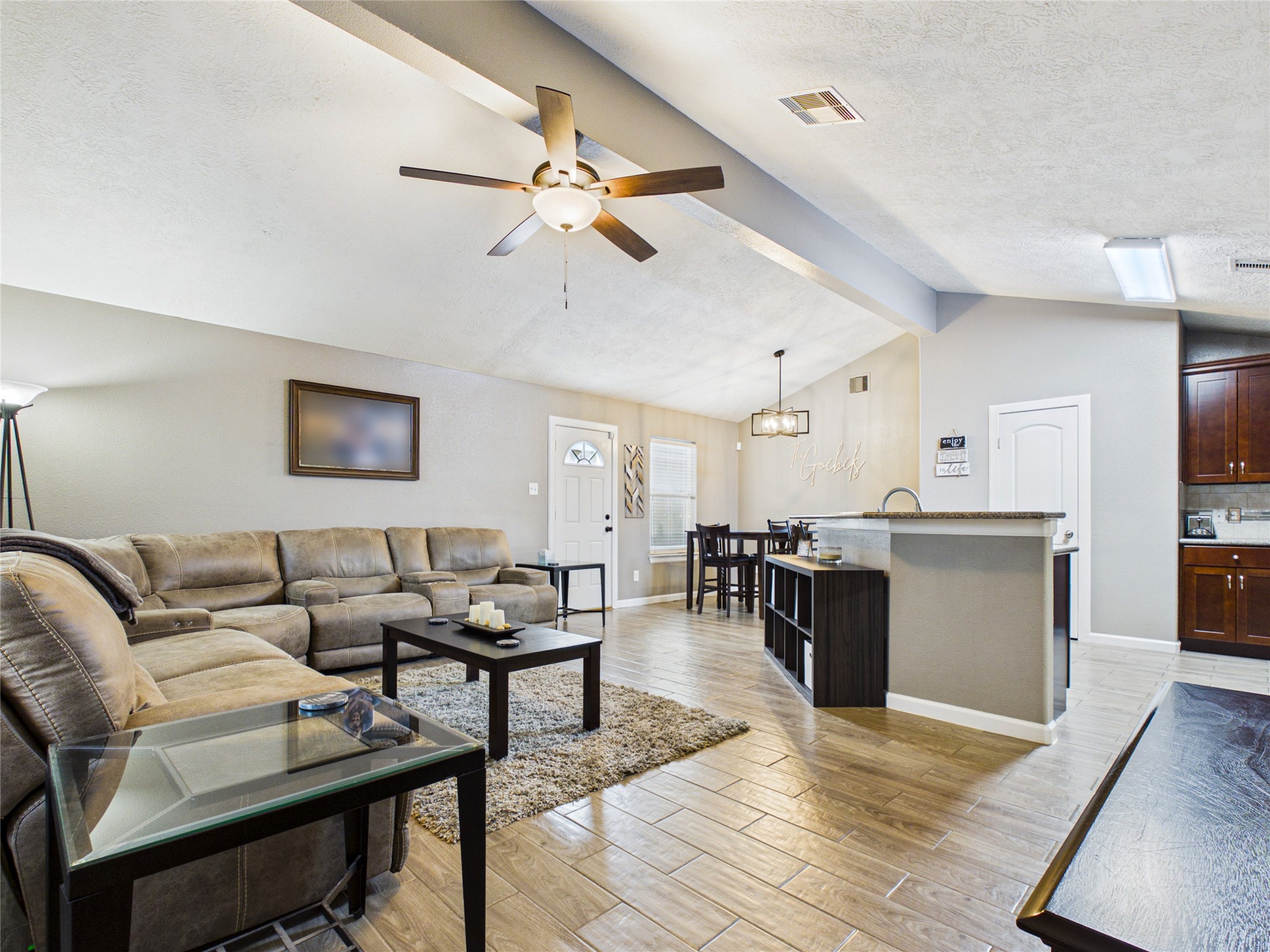 Spacious open-concept living area with vaulted ceilings, seamlessly connected to a modern kitchen with a breakfast bar and dining area. Spacious open-concept living area with vaulted ceilings, seamlessly connected to a modern kitchen with a breakfast bar and dining area.
