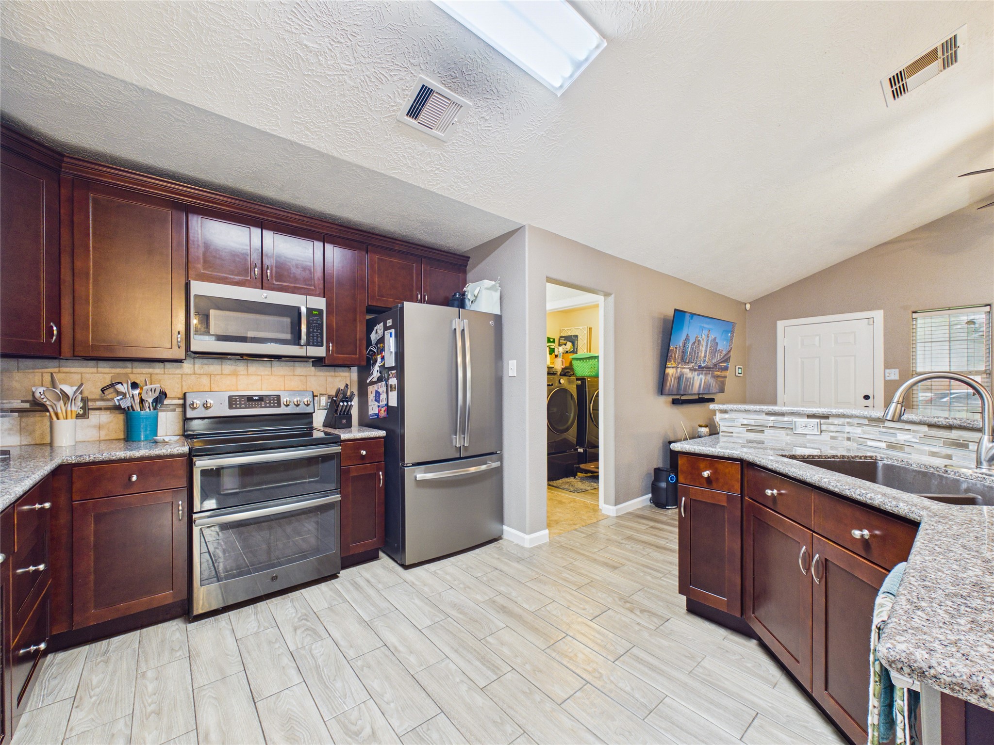 The kitchen is functional, featuring granite countertops, stainless steel appliances, and tile flooring.