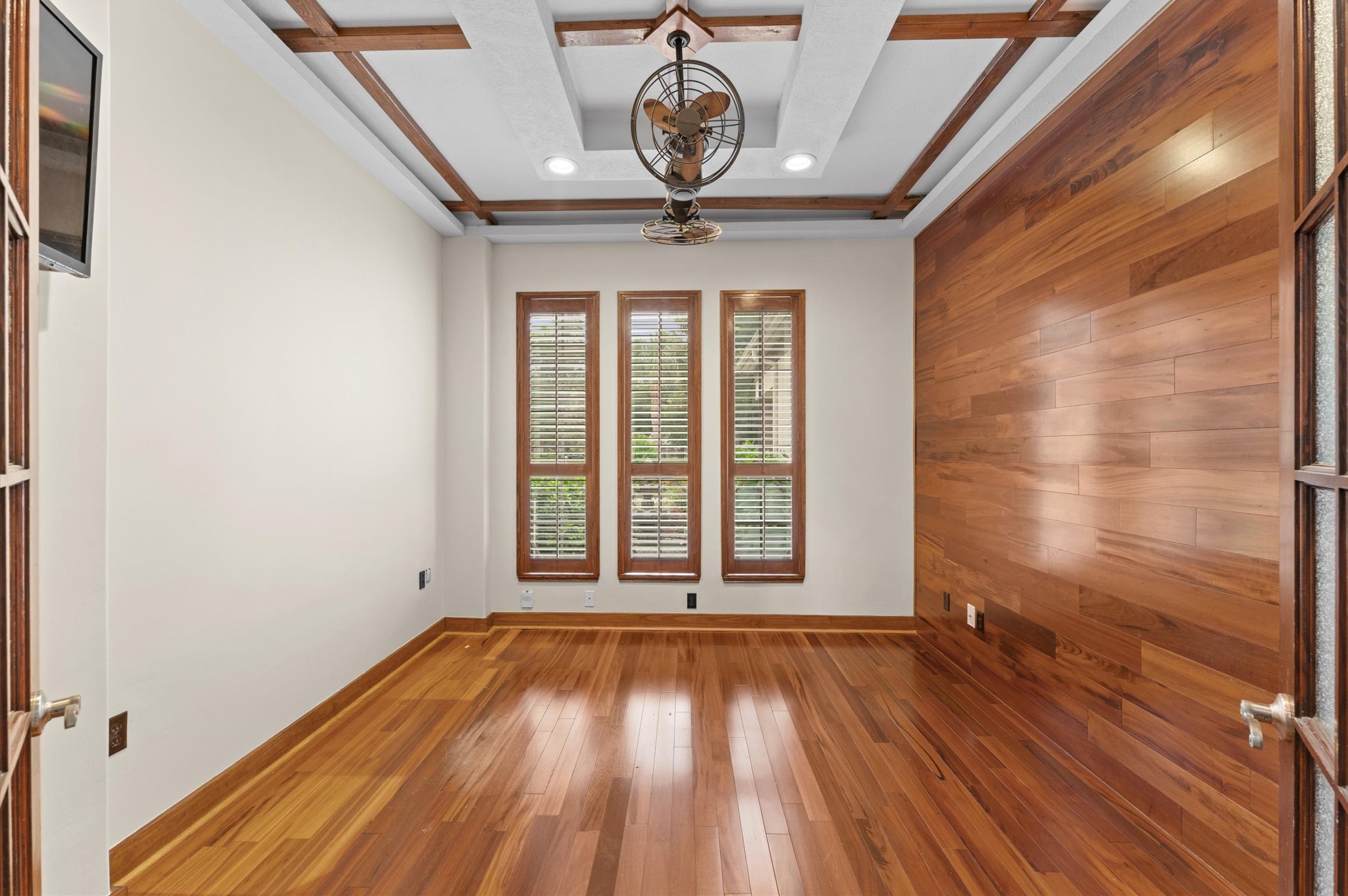 The study has luxurious wood flooring and accent wall with designer tray ceiling.