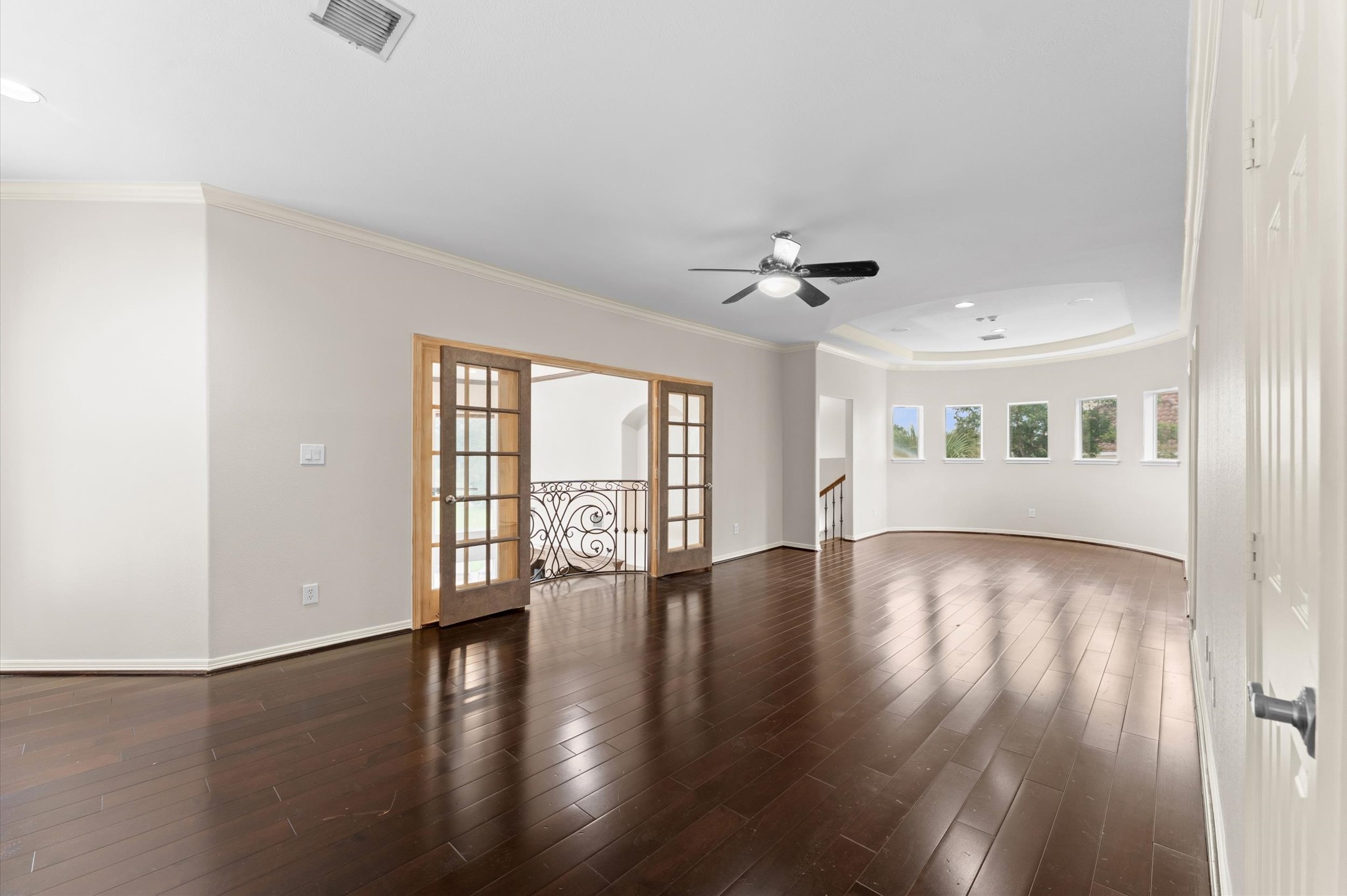 The grand room upstairs can be used as a TV or game room. The beautiful flooring and curved wall offers a luxurious feeling. The double doors open to a Juliet balcony.
