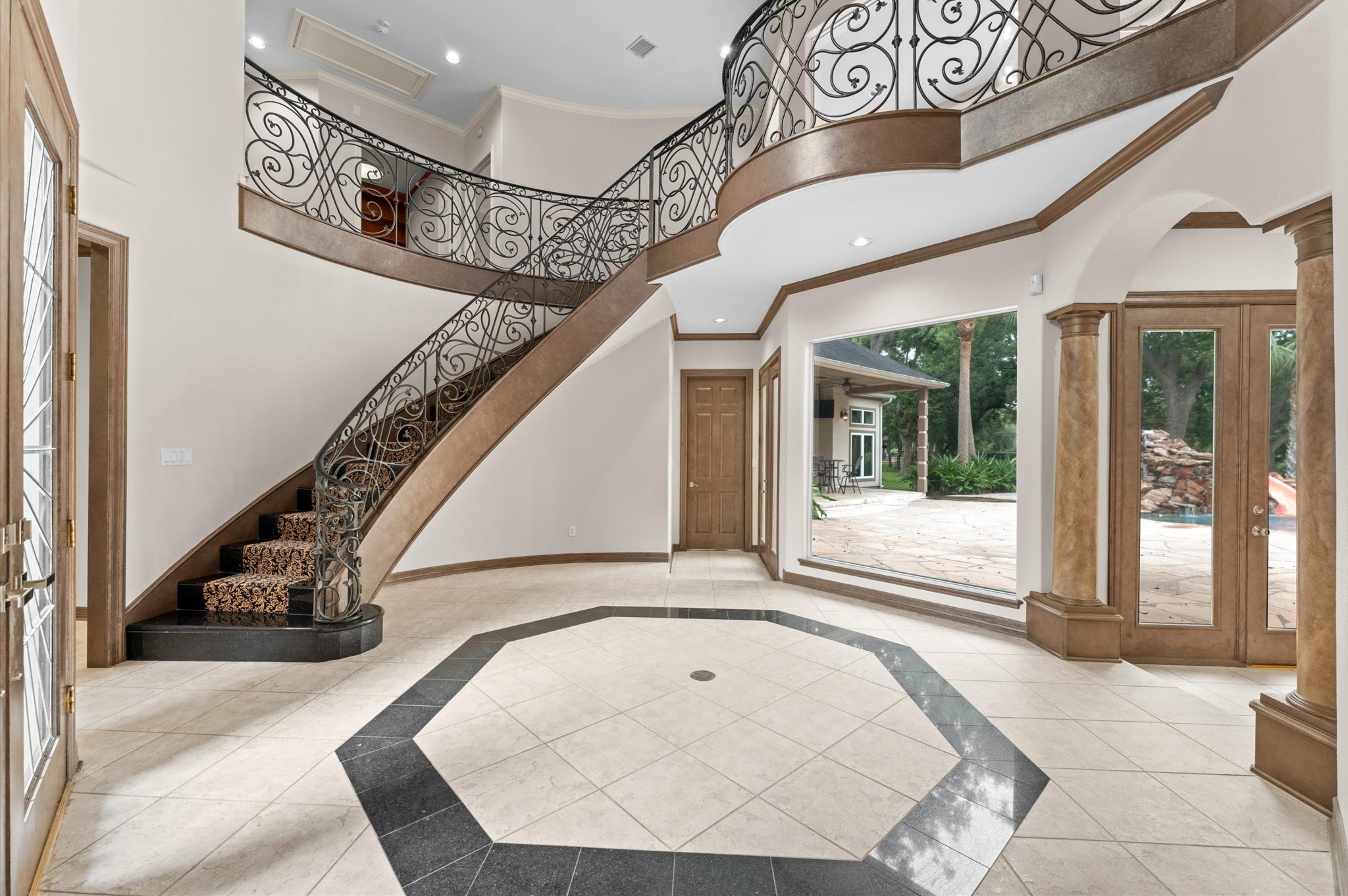 This grand foyer is a showstopper! 2-story, customized stair railing, the wall of windows looking into the backyard oasis.