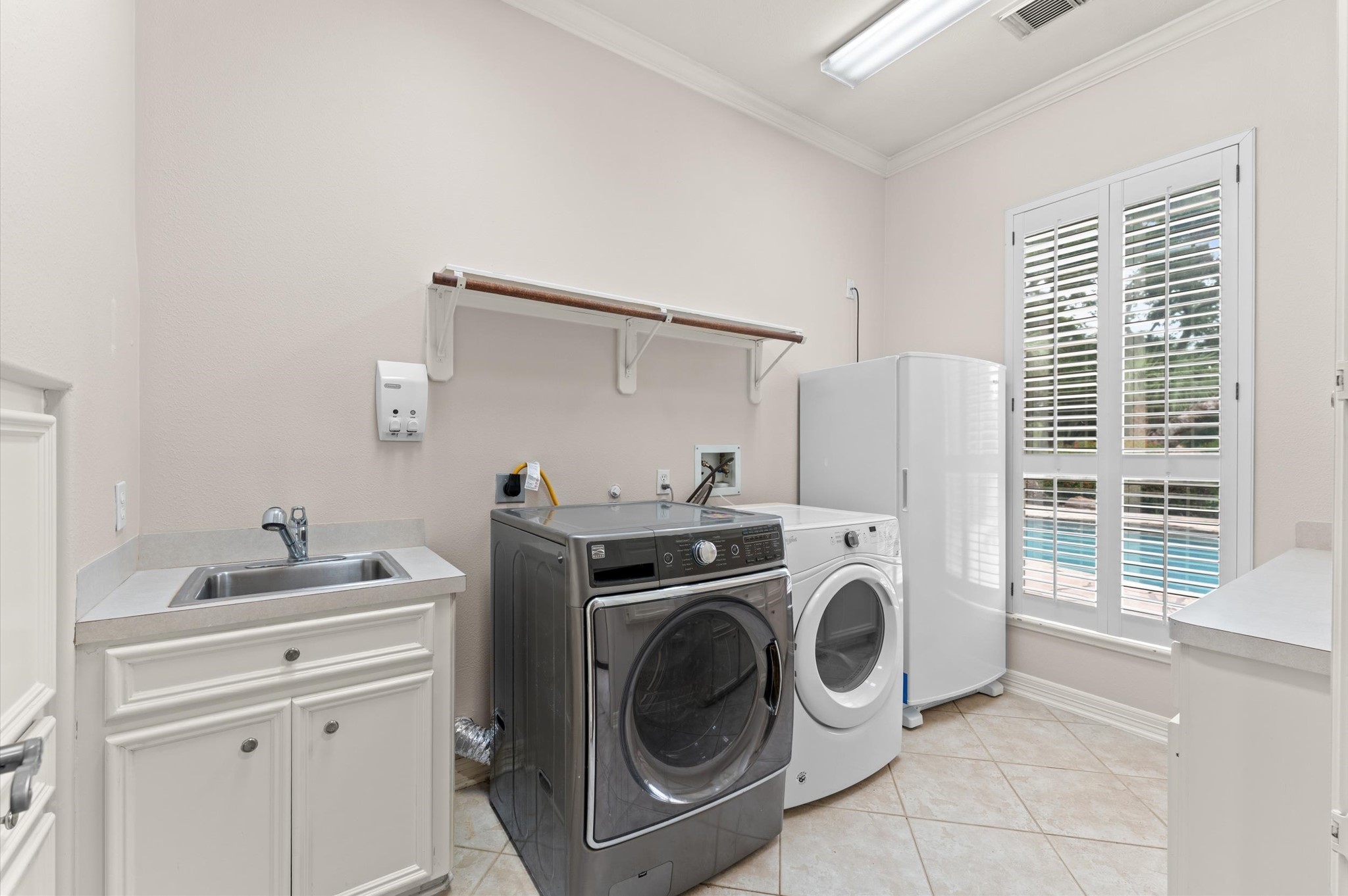 The laundry has: a sink, room for oversized washer & dryer, deep freeze, built-in cabinets, counter space for folding, built-in iron and a view of the pool!