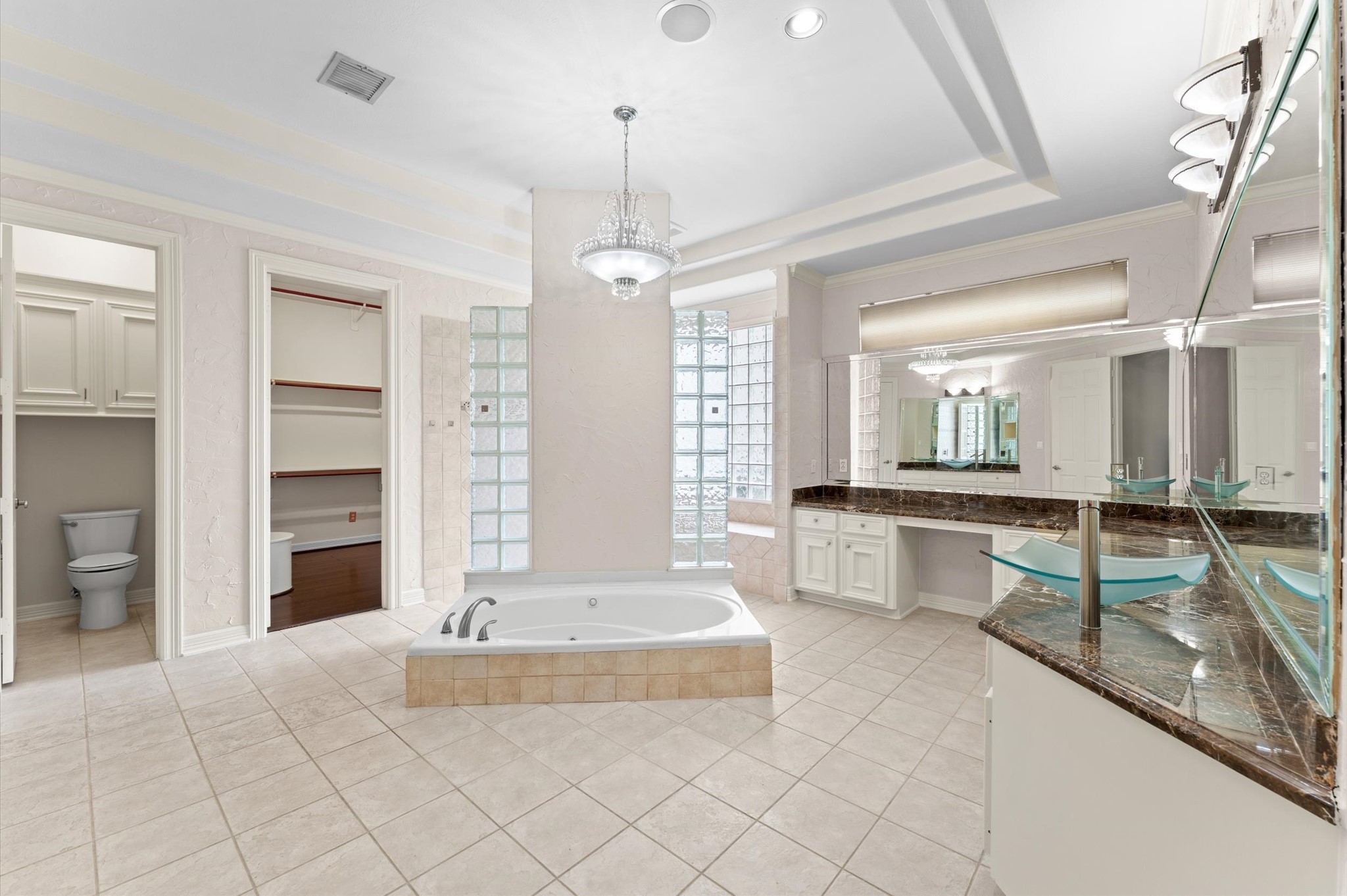 The primary bathroom has jetted tub, walk-through shower, double vanity, ample storage, private toilet closet with two walk-in closets.