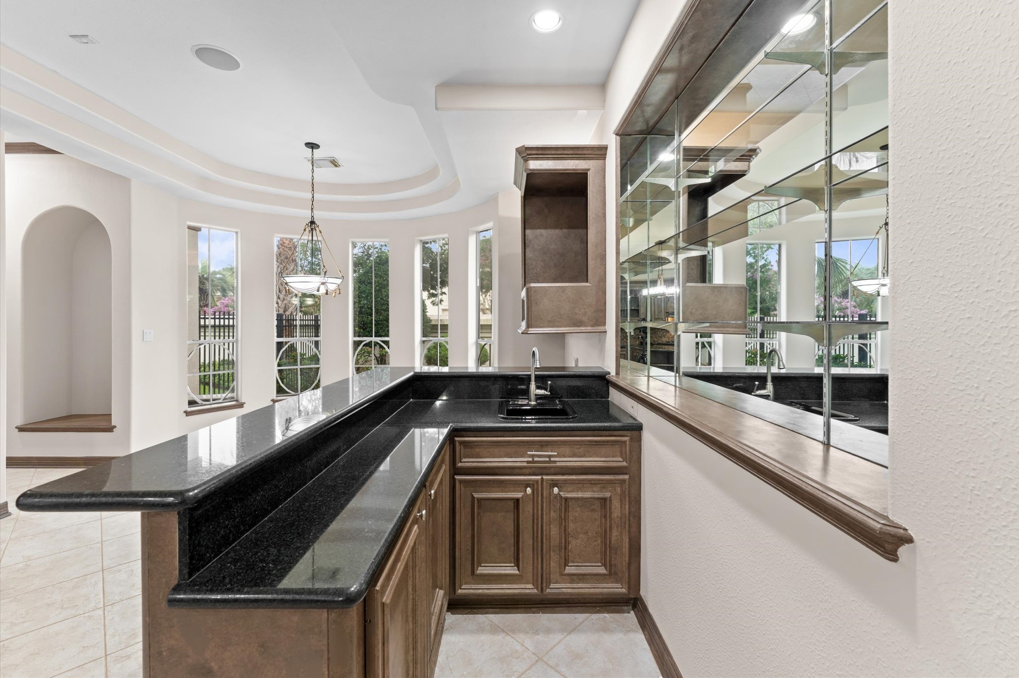A view of the wet bar which offers plenty of space for bar stools, a mirror wall where your many liquors are displayed. The breakfast room sits by the windows which is the perfect place to start your day!