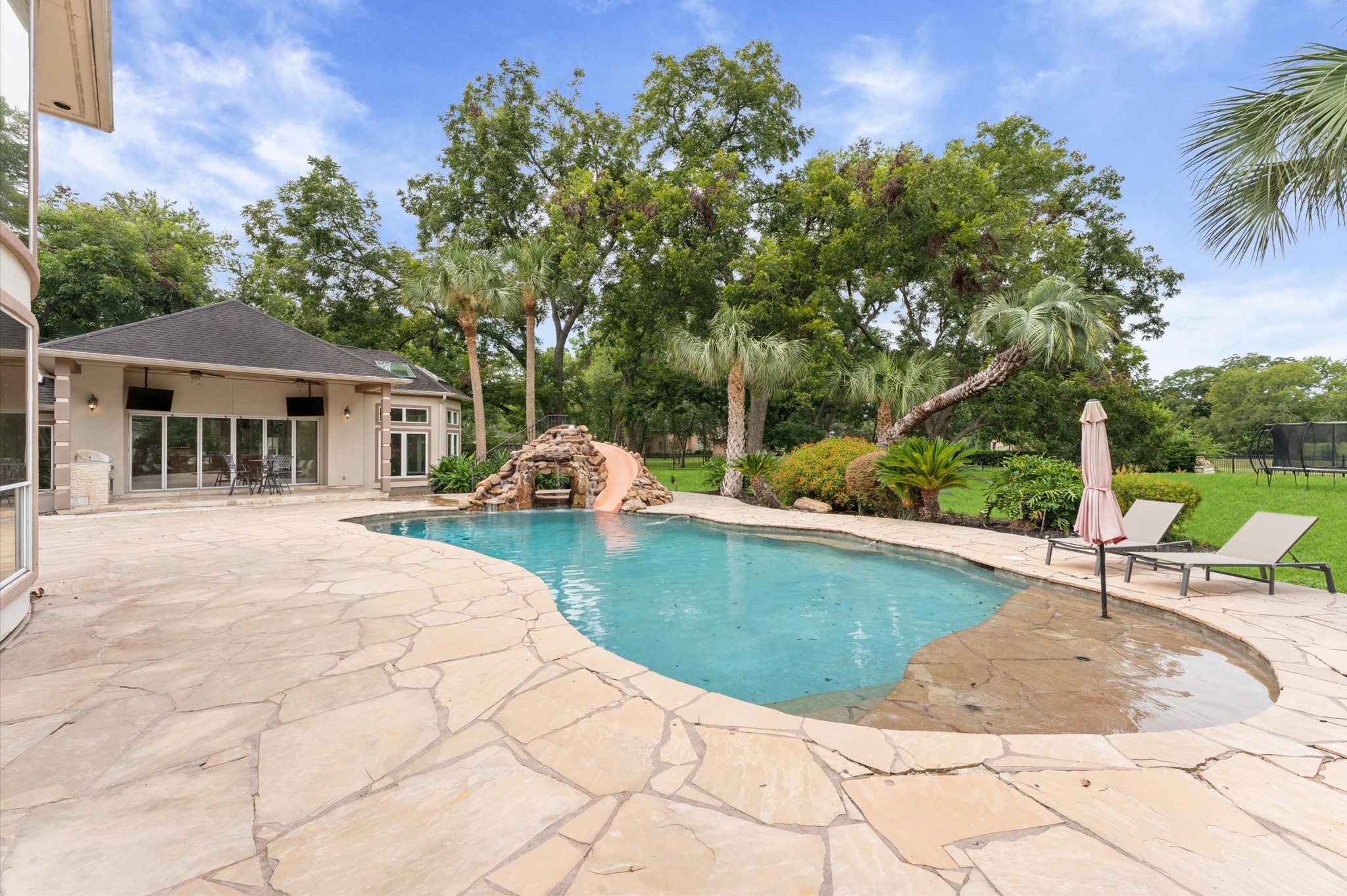 Another view of the pool has a water shelf for sunning, offers a peak into the grotto and a luxurious yard.